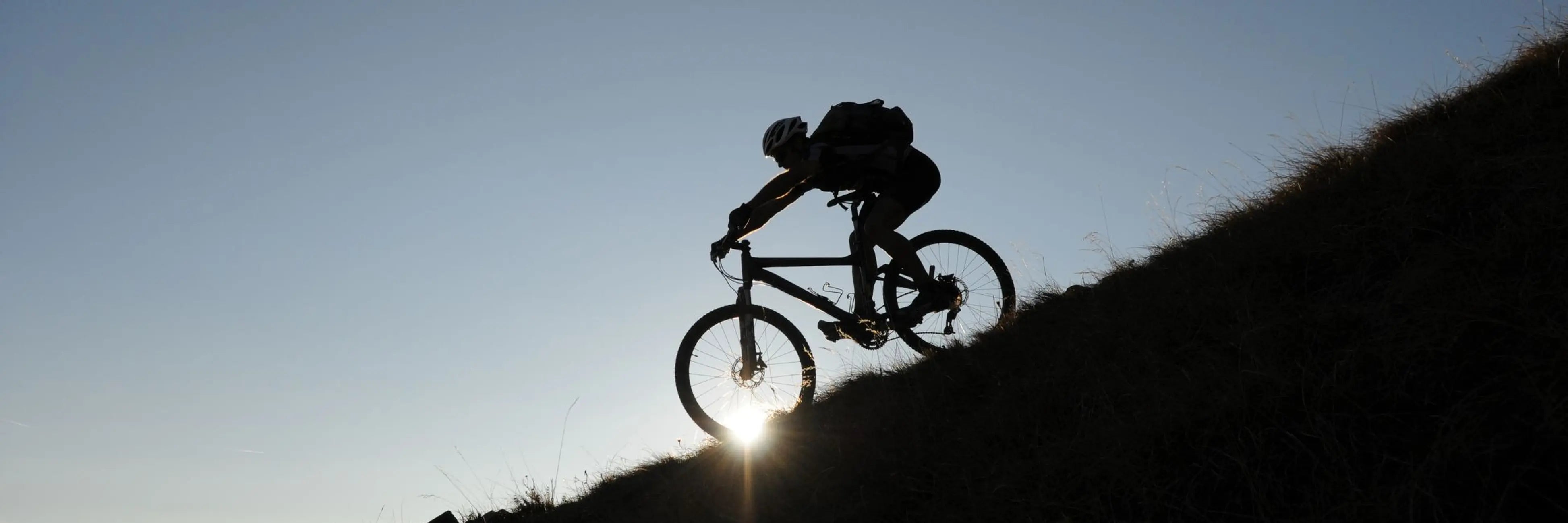 Silhouette of mountain biker riding uphill in Cascade Range at sunset