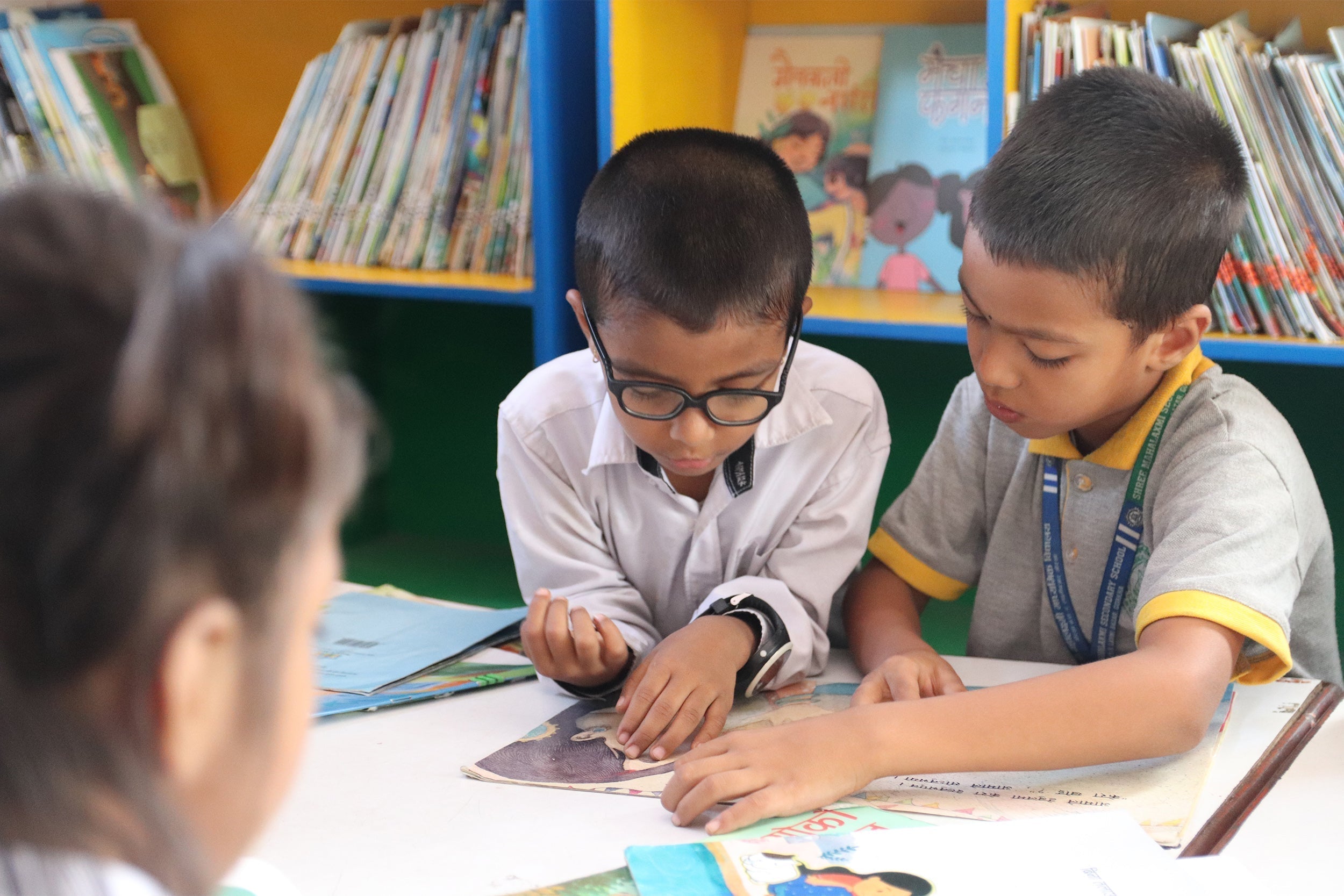 Two boys in school uniforms study open book on International Day of Education