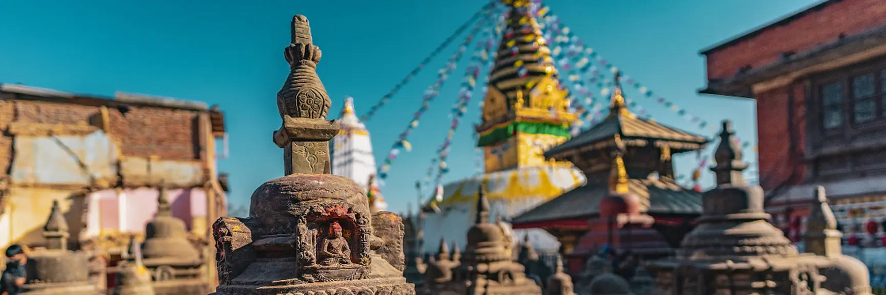 Stone stupa with intricate carvings and golden spire at Swayambhu Mahachaitya