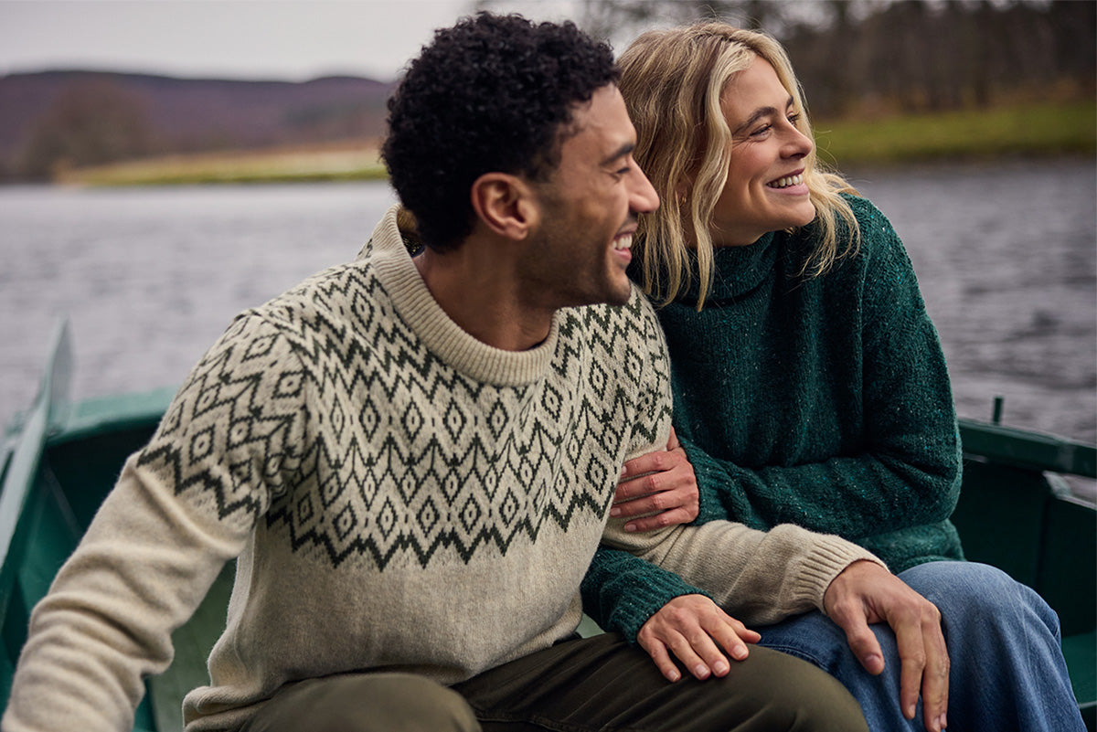 Man and woman in a boat wearing cozy knit sweaters.
