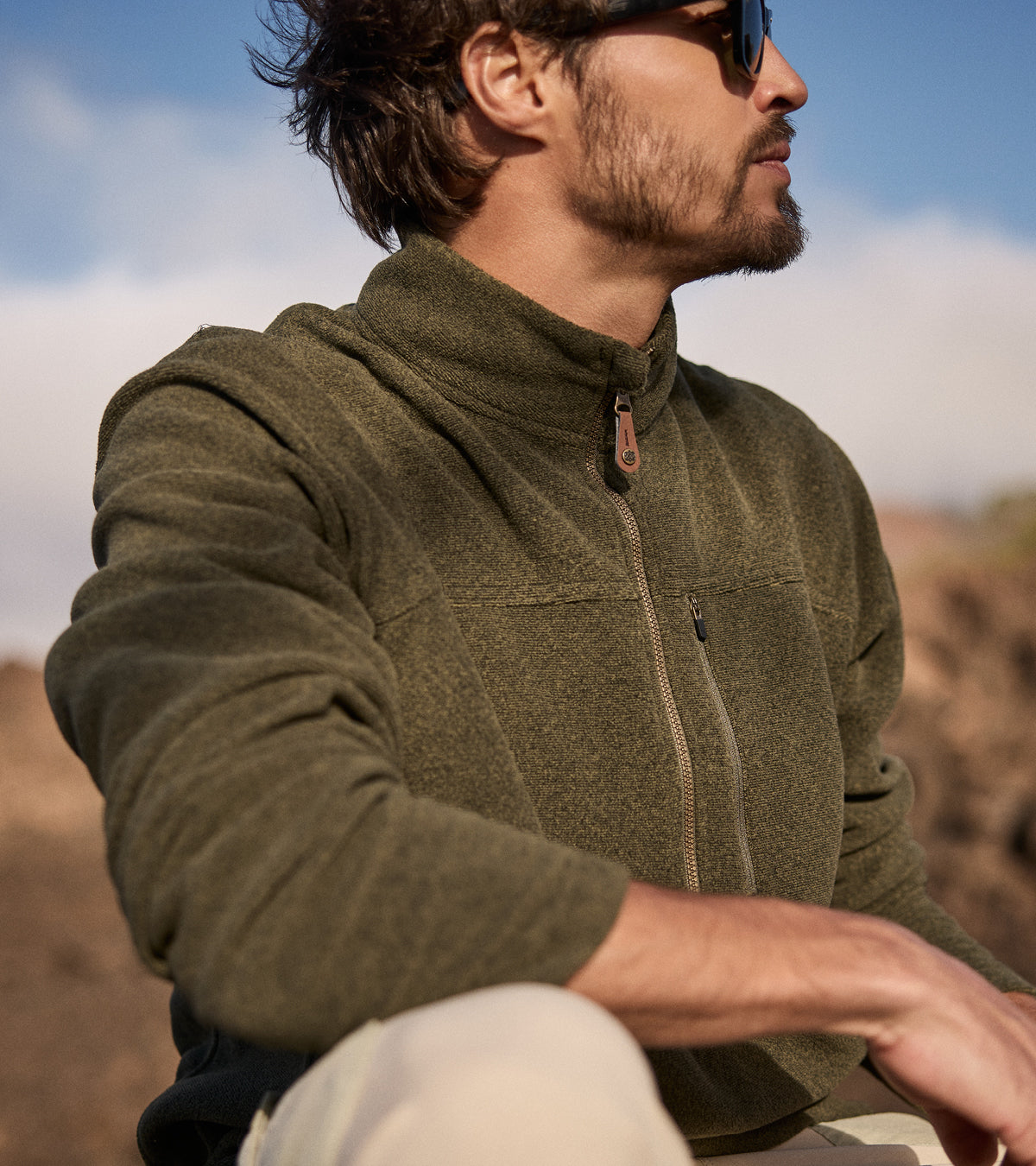 Man wearing a green fleece jacket outdoors with a blurred natural background