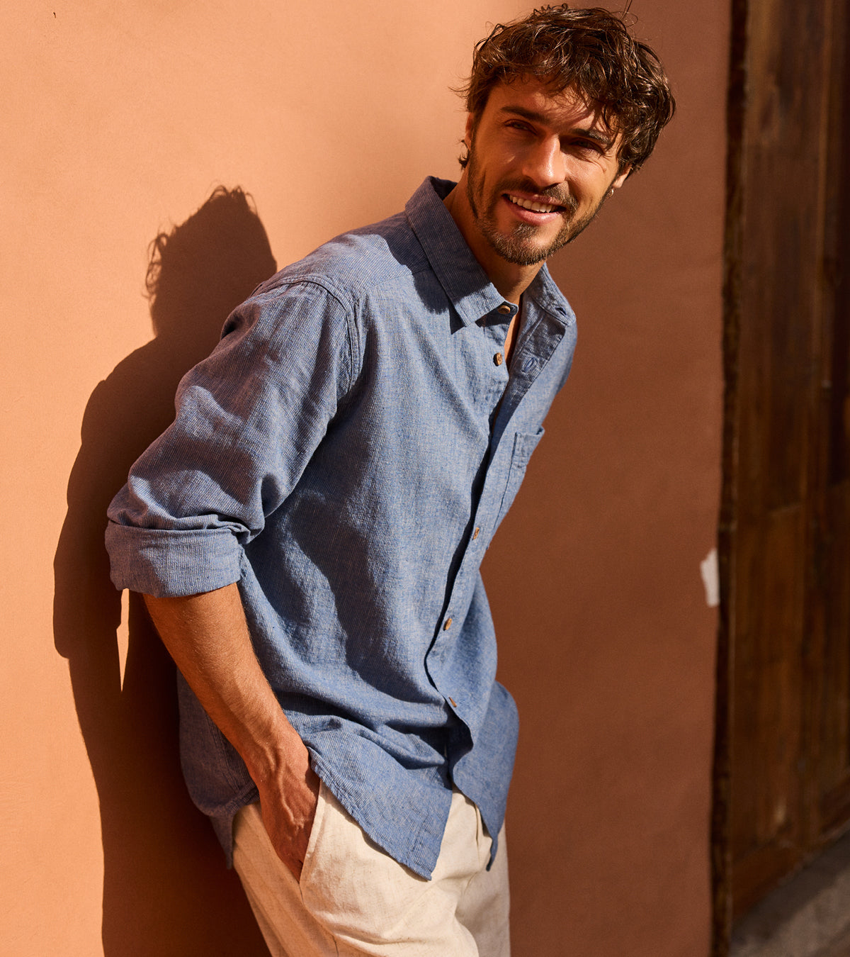 Man wearing a blue shirt against a brown wall