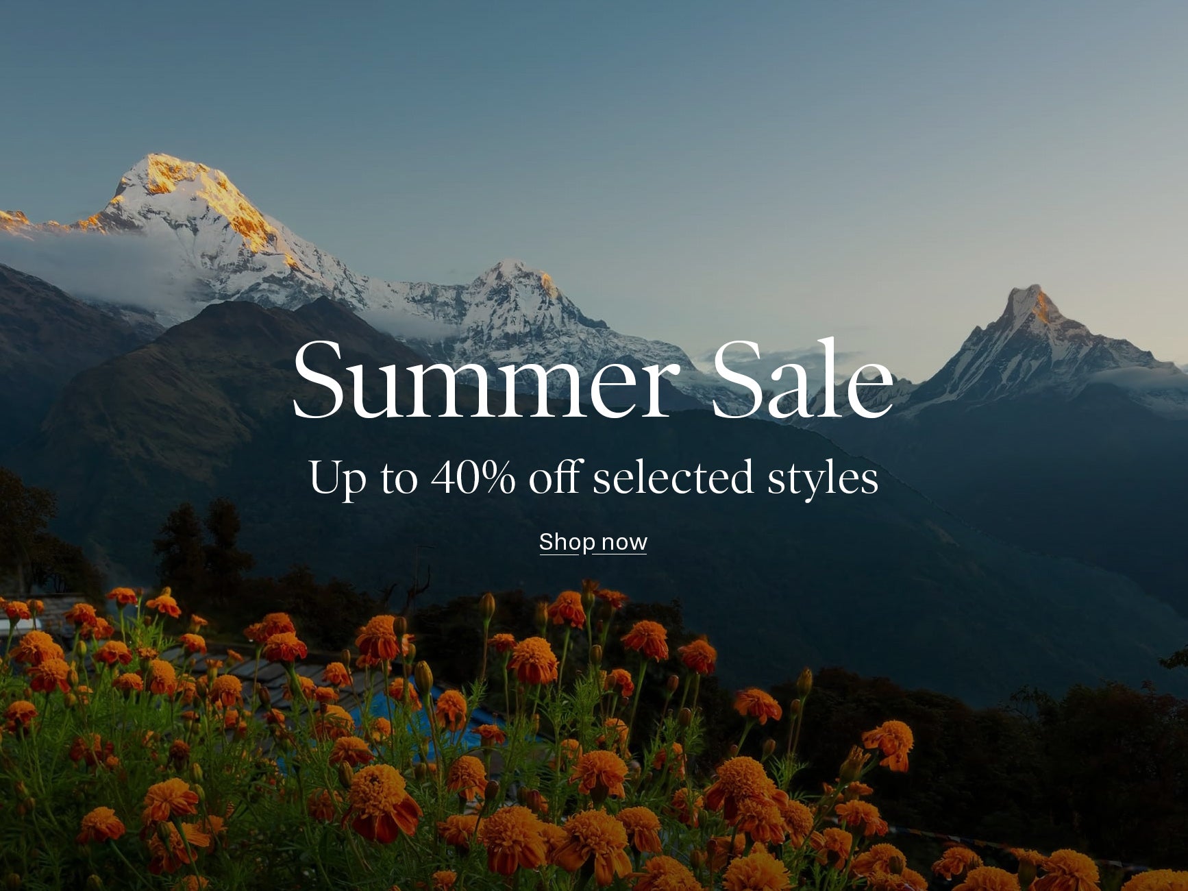 Mountain landscape with snow-capped peaks, orange flowers in the foreground, and overlaid sale text reading 'Summer Sale', 'Up to 40% off selected styles', and 'Shop now'.