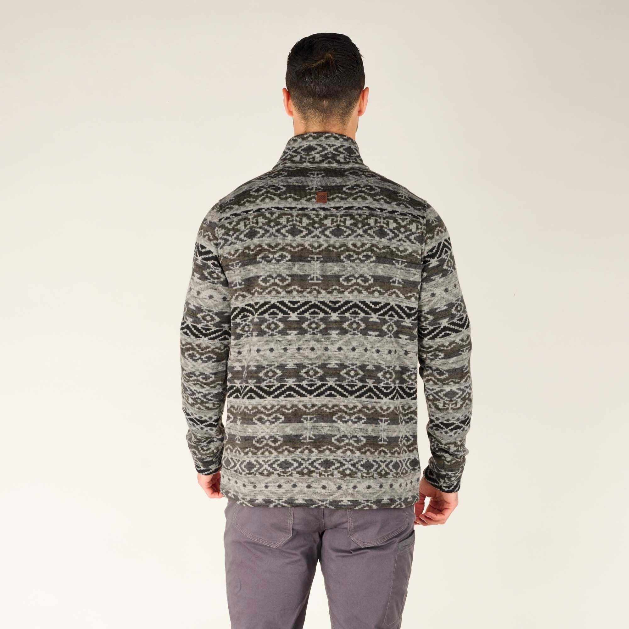 A back shot of the Sherpa Adventure Gear Bhutan Pullover in Grey, showcasing its full design, including a continuation of the intricate geometric patterns across the back. The model's posture highlights the pullover's cozy fit and high-quality material.