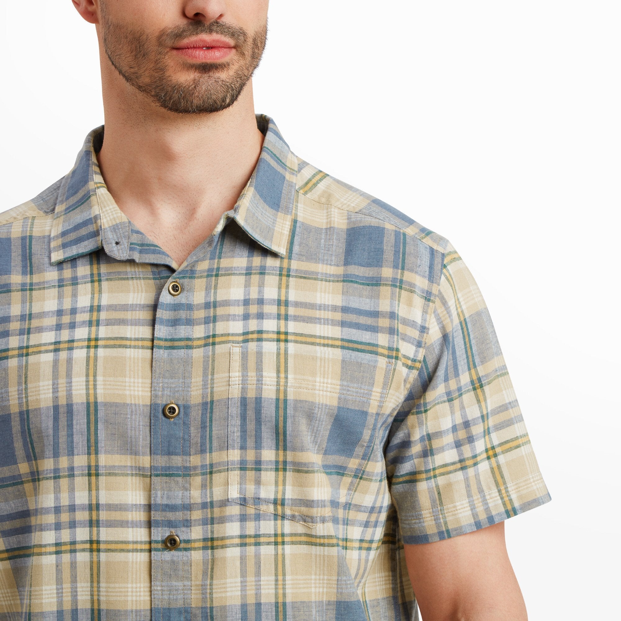 A detailed view of the upper front section of the Sherpa Adventure Gear Hosh Plaid Short Sleeve Shirt in Beige, focusing on the fabric texture, button details, and chest pocket. This image highlights the craftsmanship and color pattern of the shirt.