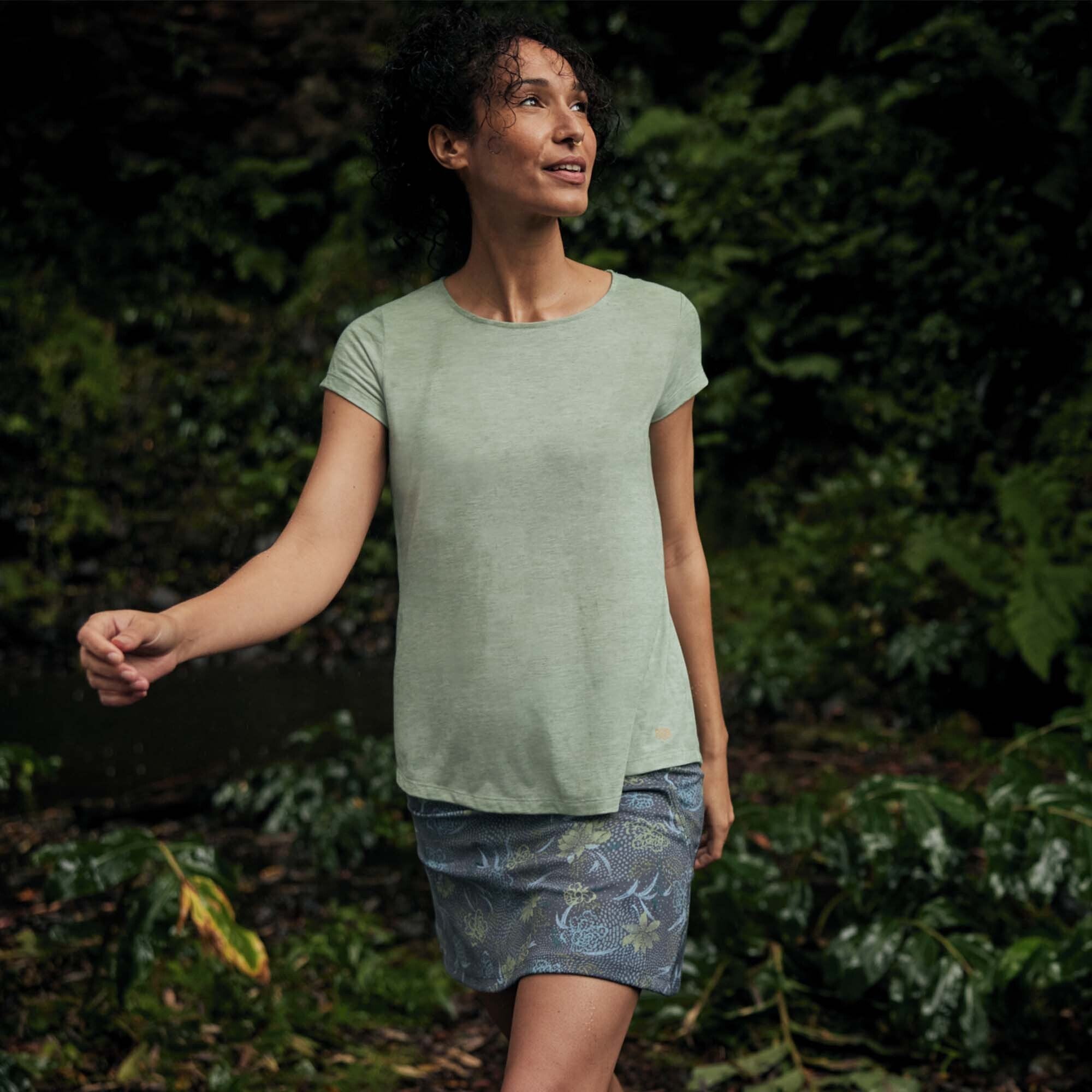 A model is seen walking through a rainforest looking to the above canope wearing a mint t-shirt and a Sherpa Adventure Gear Nisha Skort in Blue