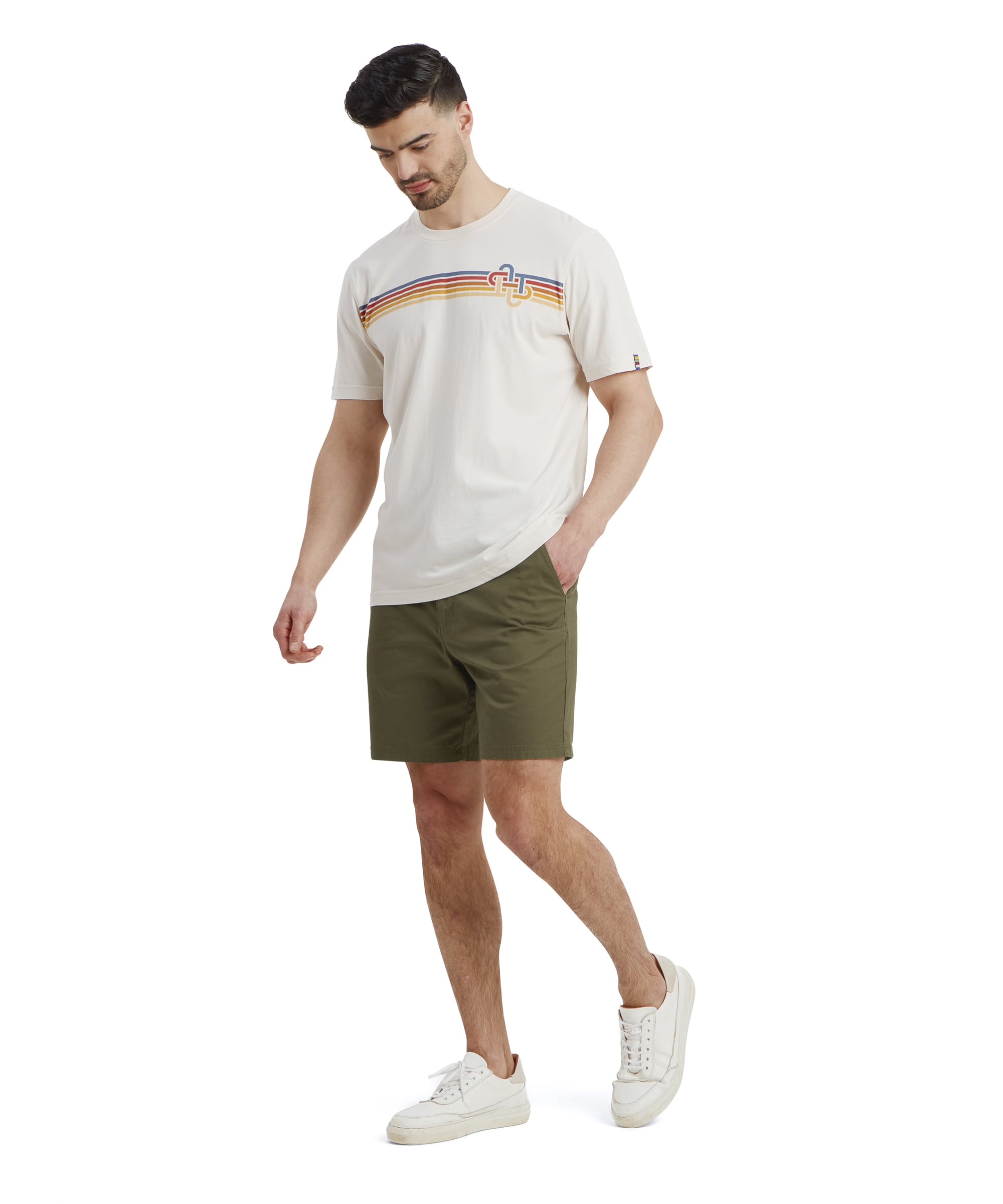An angled side-front view showing the tailored fit of the Sherpa Adventure Gear Tenjing Tour Shorts in Green. The pocket detail is slightly visible, and the clean stitching adds to the structured design. The model stands casually, highlighting the comfort and practicality of the shorts.