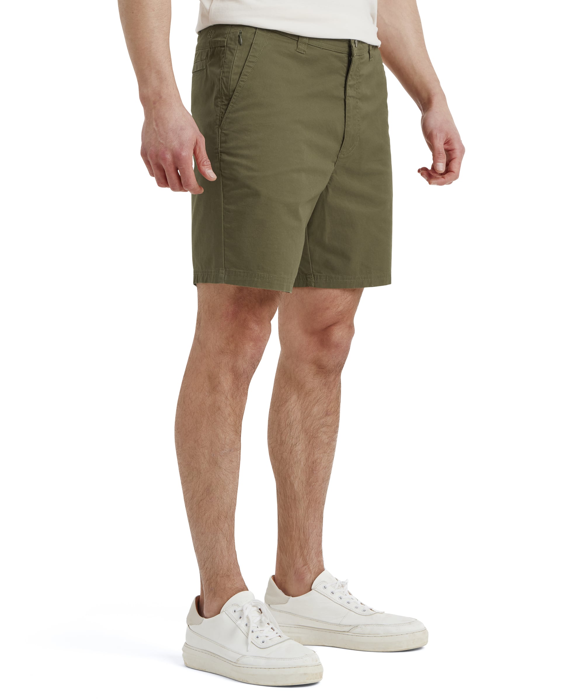 A back view of the Sherpa Adventure Gear Tenjing Tour Shorts in Green reveals rear welt pockets for a streamlined appearance. The fabric appears smooth and lightweight, suitable for casual or outdoor activities. The model's stance highlights the overall fit and length of the shorts.