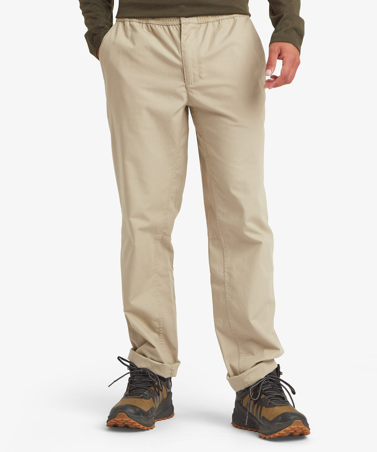 Eine Vorderansicht der beigen Hose mit elastischem Bund, Seitentaschen und geradem Bein, kombiniert mit Outdoor-Wanderschuhen.
