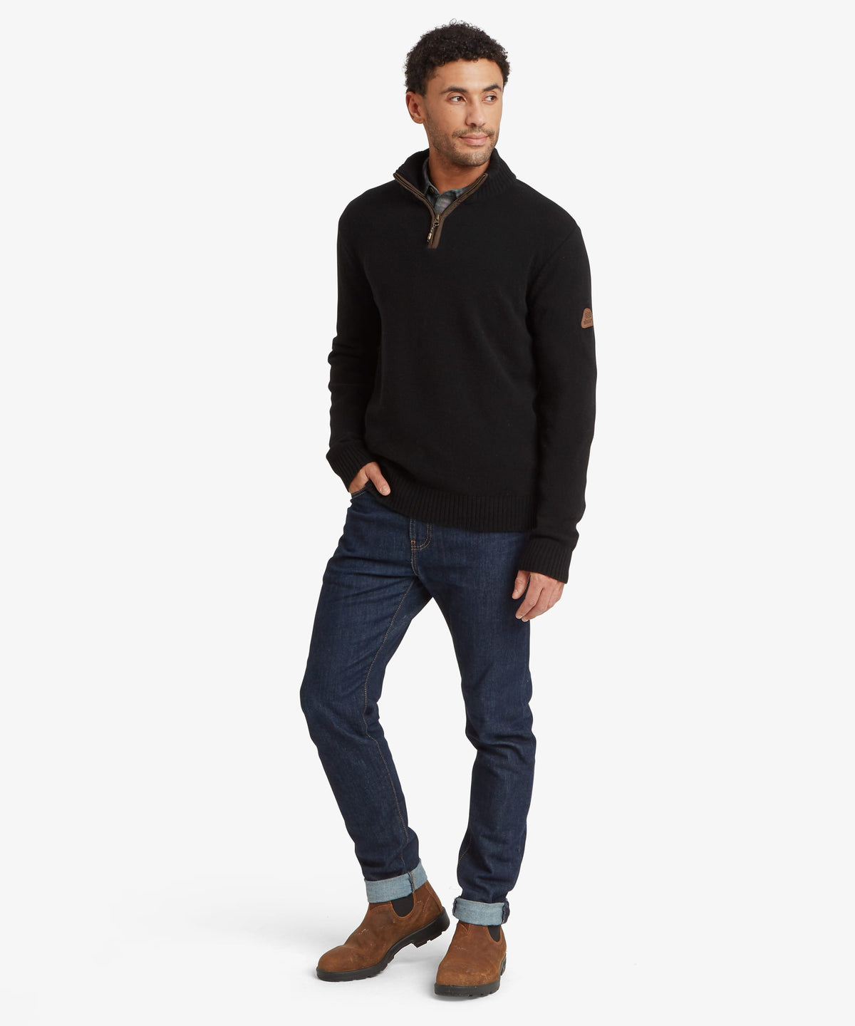 A man modeling a black quarter-zip pullover sweater with a brown sleeve patch.