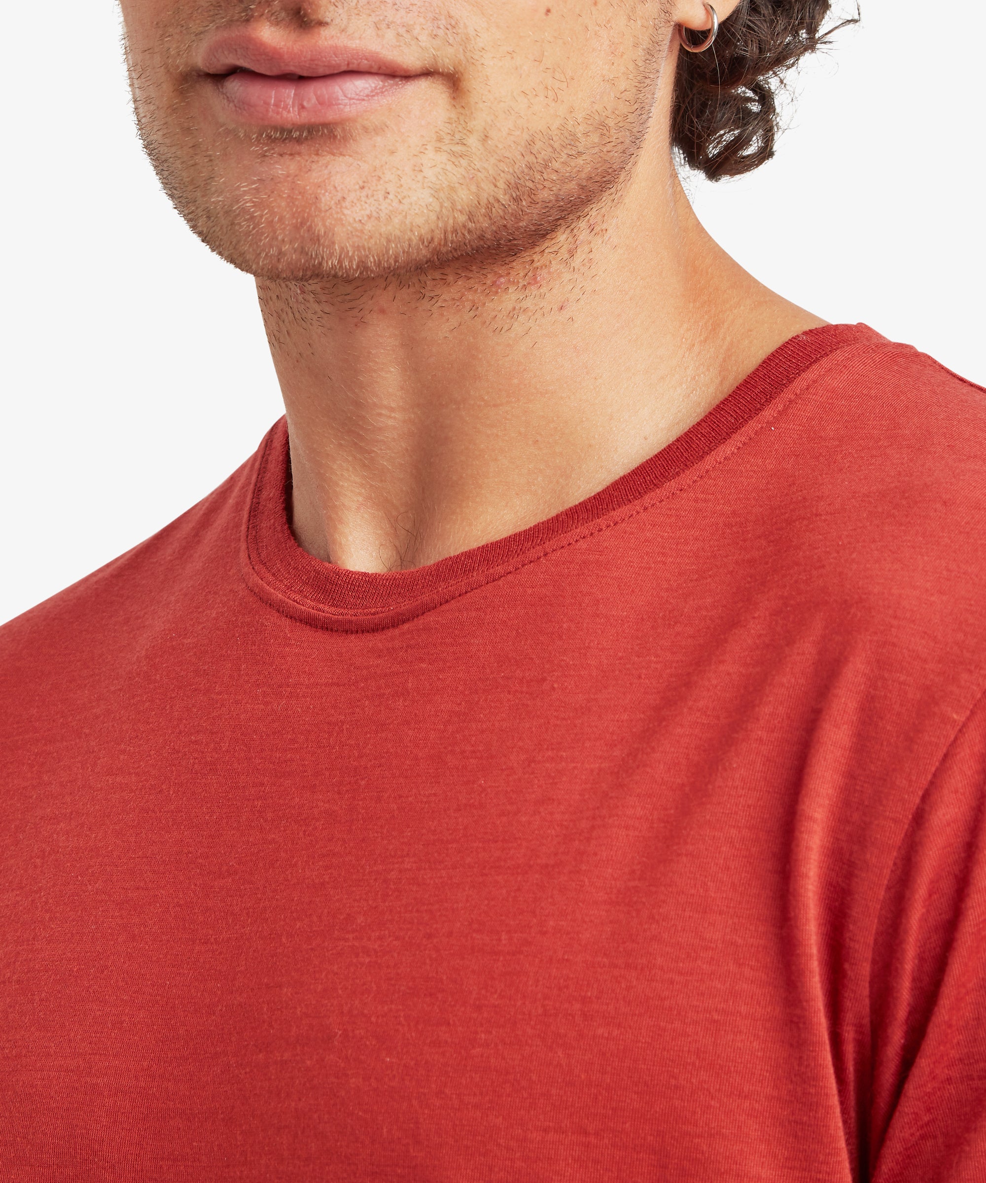 A close-up of a rust‑red Merino wool T‑shirt showing the crew neckline and fine fabric texture.