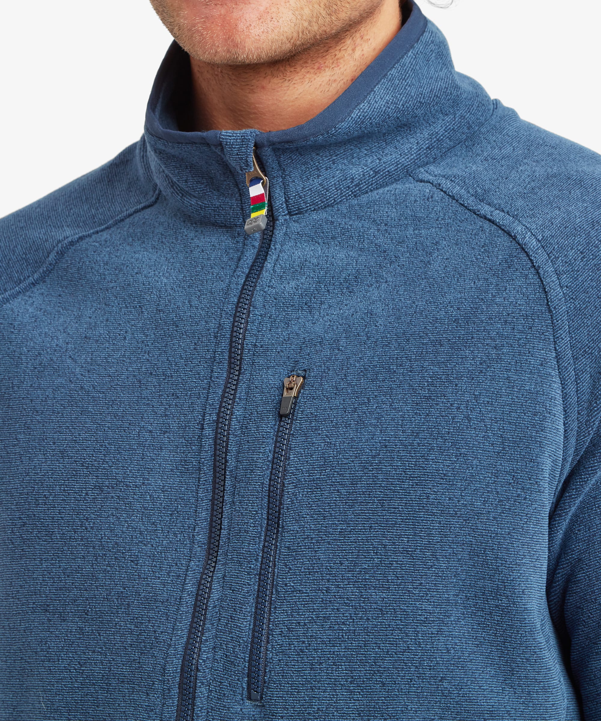 Close-up of the upper chest and collar of a heathered blue quarter-zip fleece. Features include a high stand collar, contrast zipper pull and a vertical zip chest pocket with coloured trim detail.