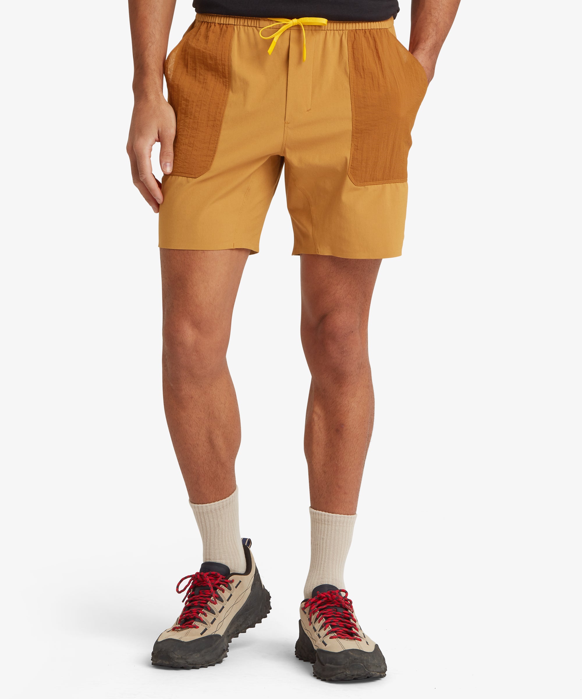 Person wearing mustard yellow shorts with a white background