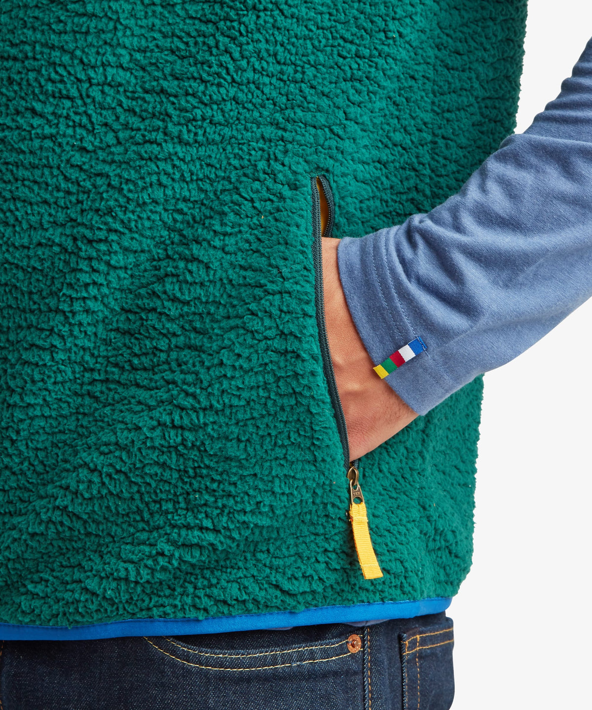 Close-up of a person in a teal green sherpa fleece zippered jacket over a blue long-sleeve top.