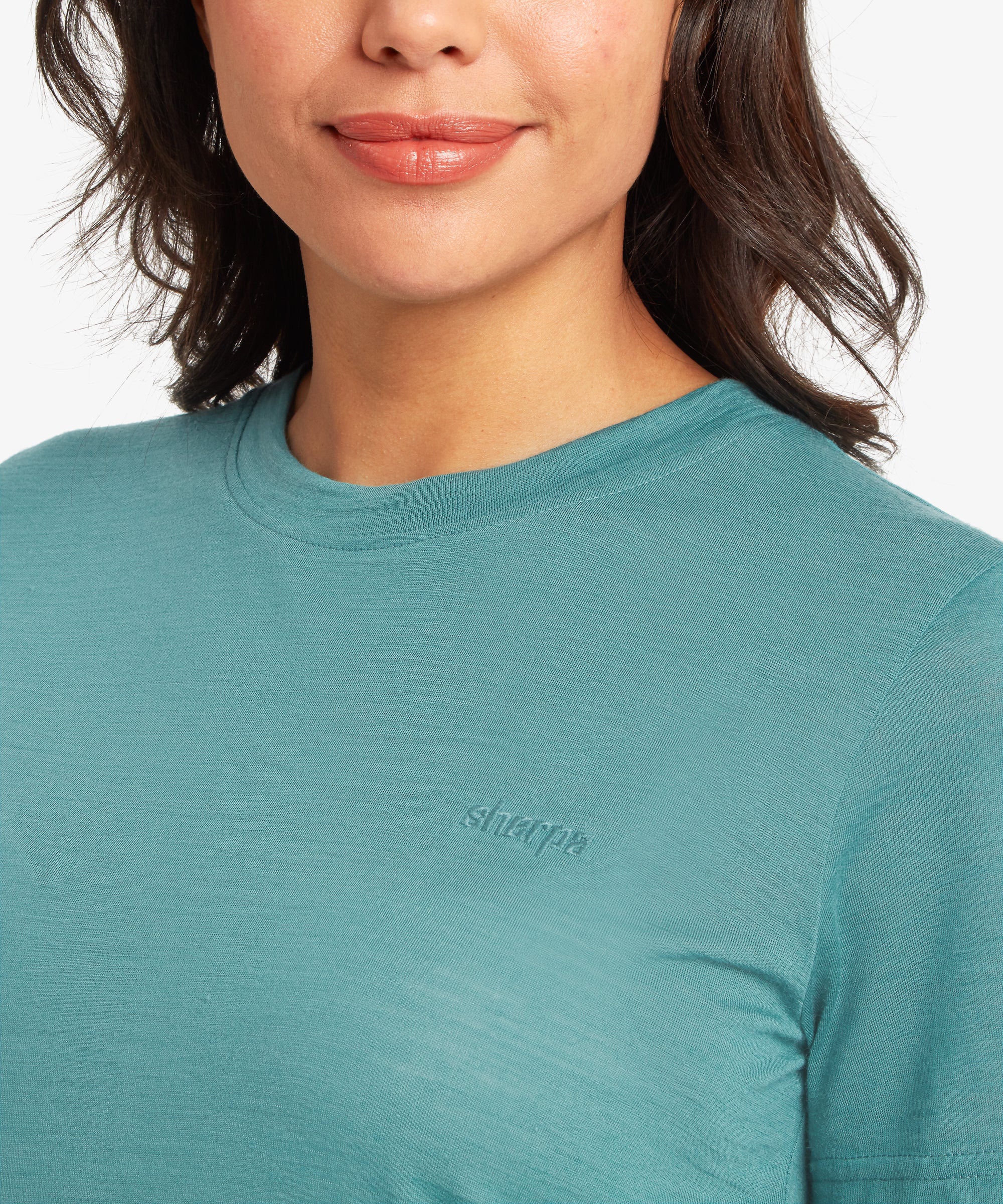 Close up of a Teal t-shirt with a Sherpa logo worn by a person