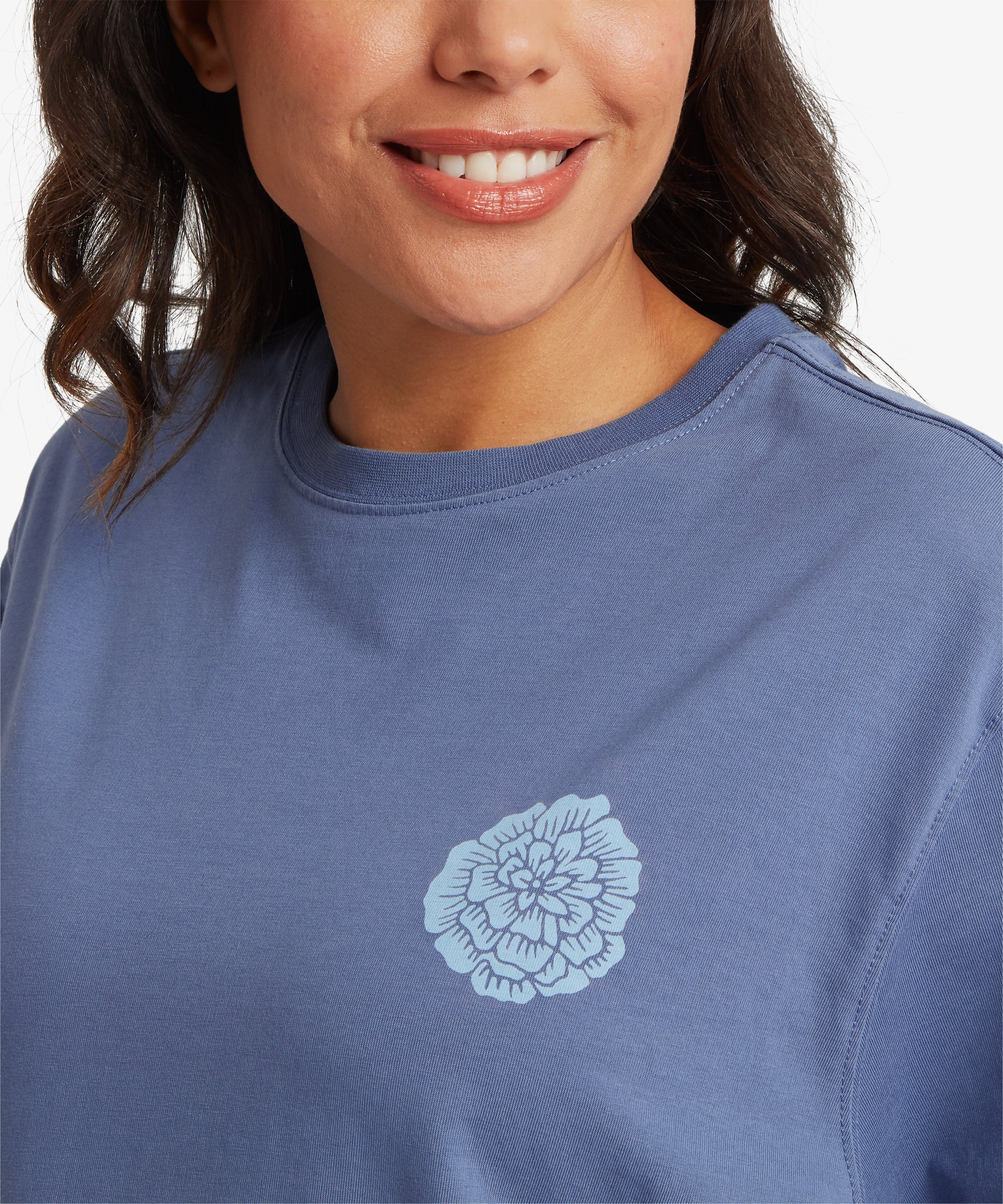 Close-up of blue T‑shirt featuring a small light-blue marigold floral graphic printed on the left chest.