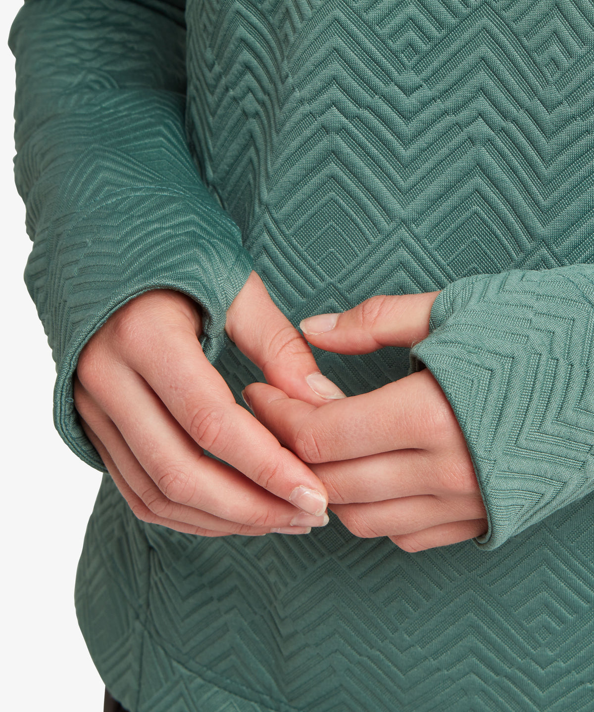 Close-up of a person wearing a textured sage green knit top with a geometric chevron pattern.