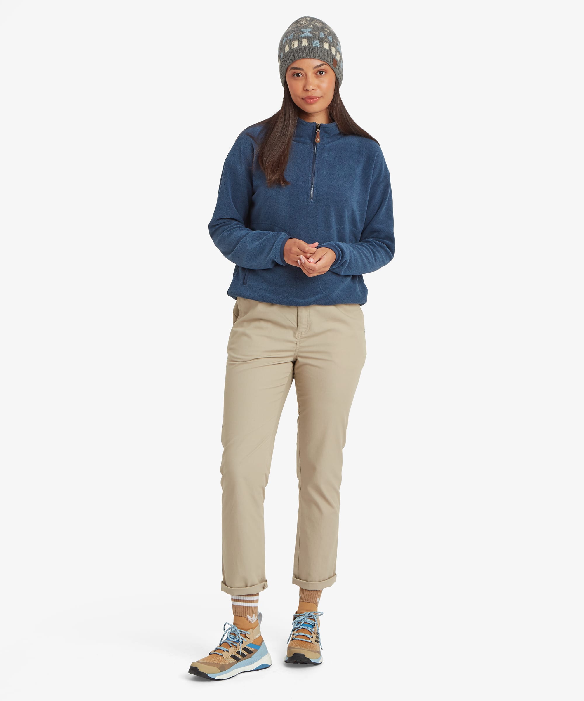Full-body front view of a woman wearing a blue half-zip fleece pullover and knit beanie. The pullover features a stand collar, soft fleece construction, and relaxed silhouette for casual outdoor wear.