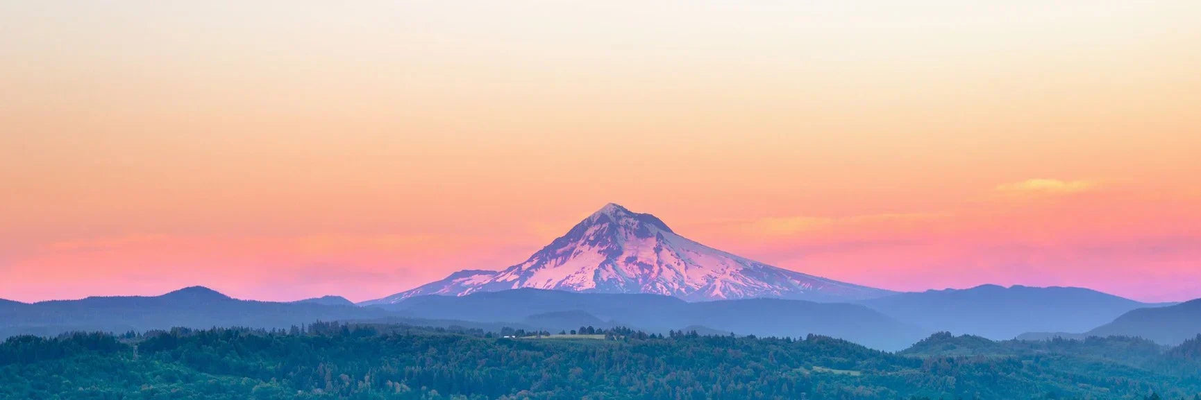 Snow-capped conical peak of Mount Hood against pink orange sunset sky