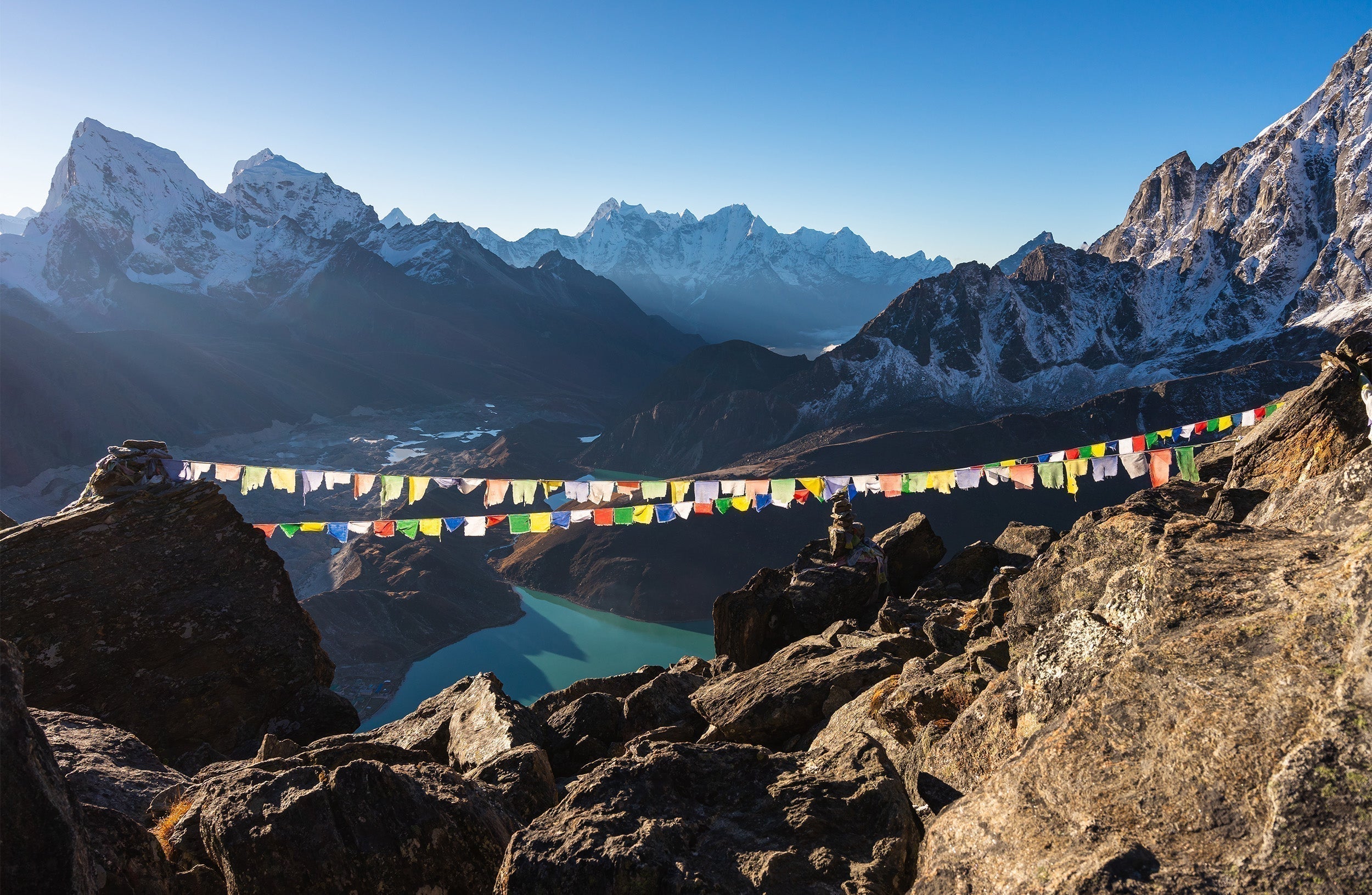 Colorful prayer flags strung between rocky peaks of Nepals highest mountains