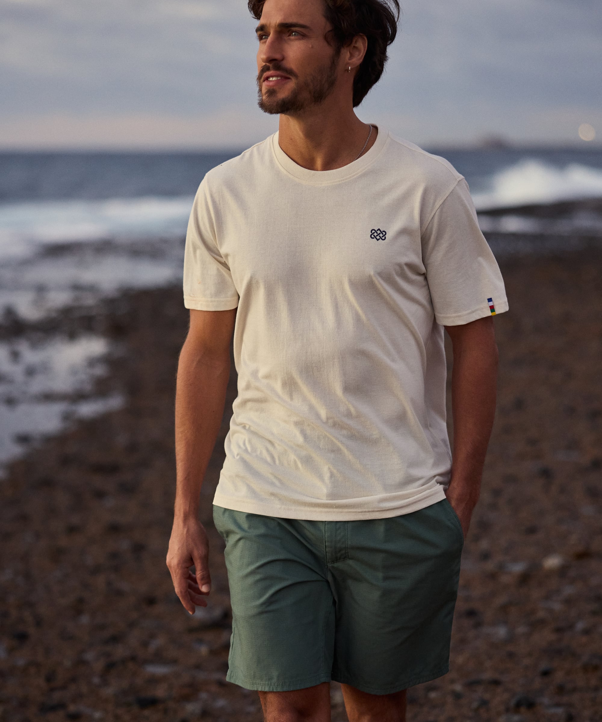 Ghoral Shorts Dark Thyme cremefarbenes T-Shirt mit schwarzem Logo und gestreiften BŸndchen