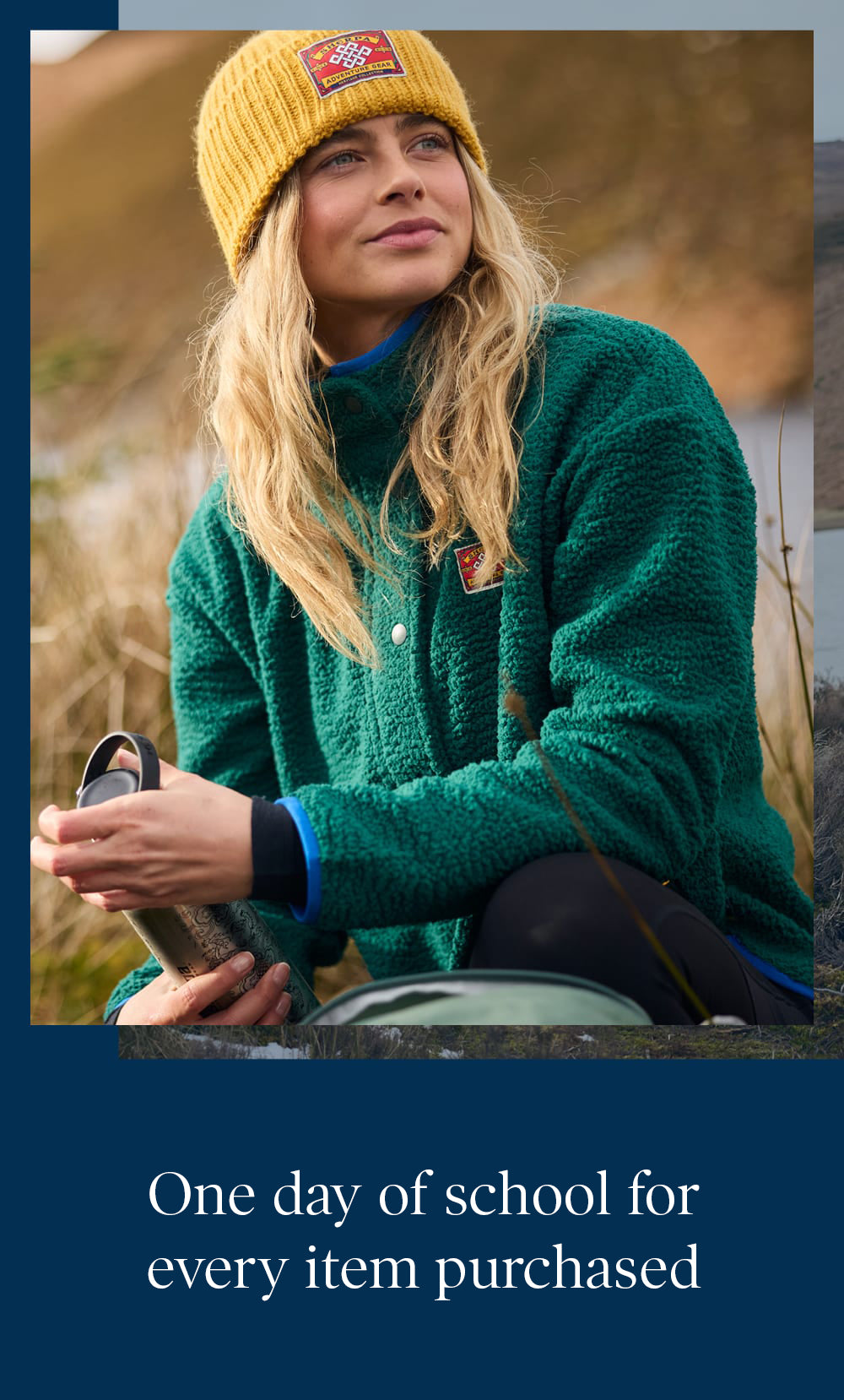 Woman in a yellow beanie and green fleece holding a black flask outdoors.