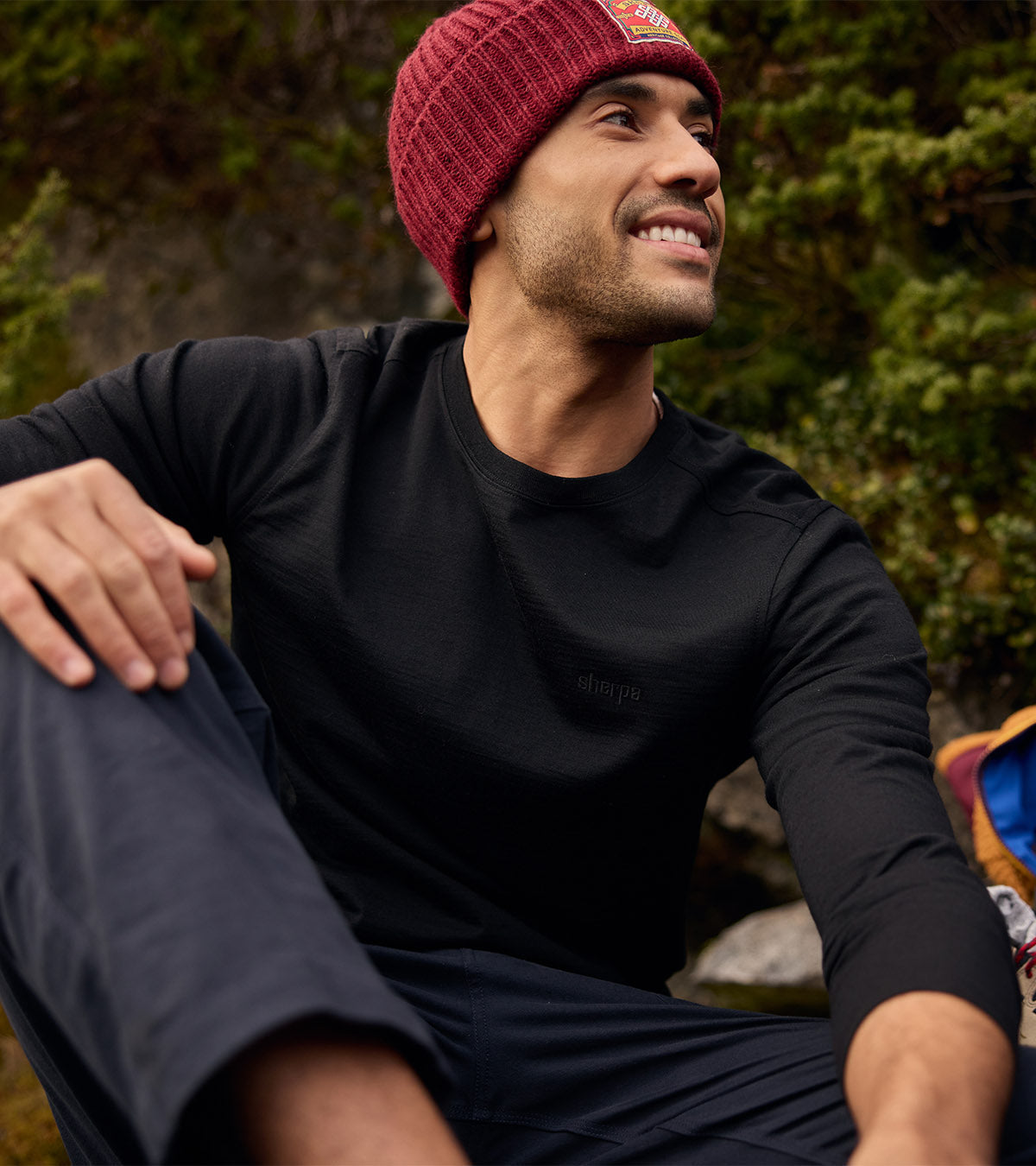 Man in maroon knit beanie and black merino long-sleeve top outdoors
