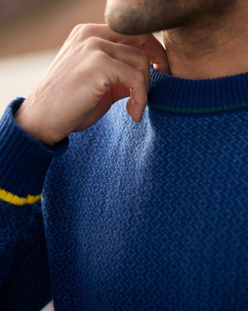 Close-up of textured blue wool jumper with yellow stripe cuff detail