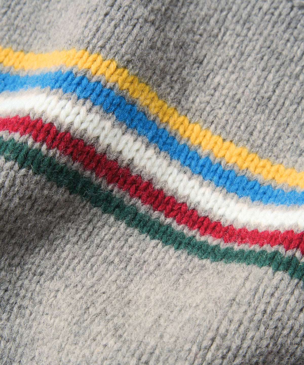 Close-up of a gray knit fabric with a wavy stripe pattern in yellow, blue, white, red, and green.