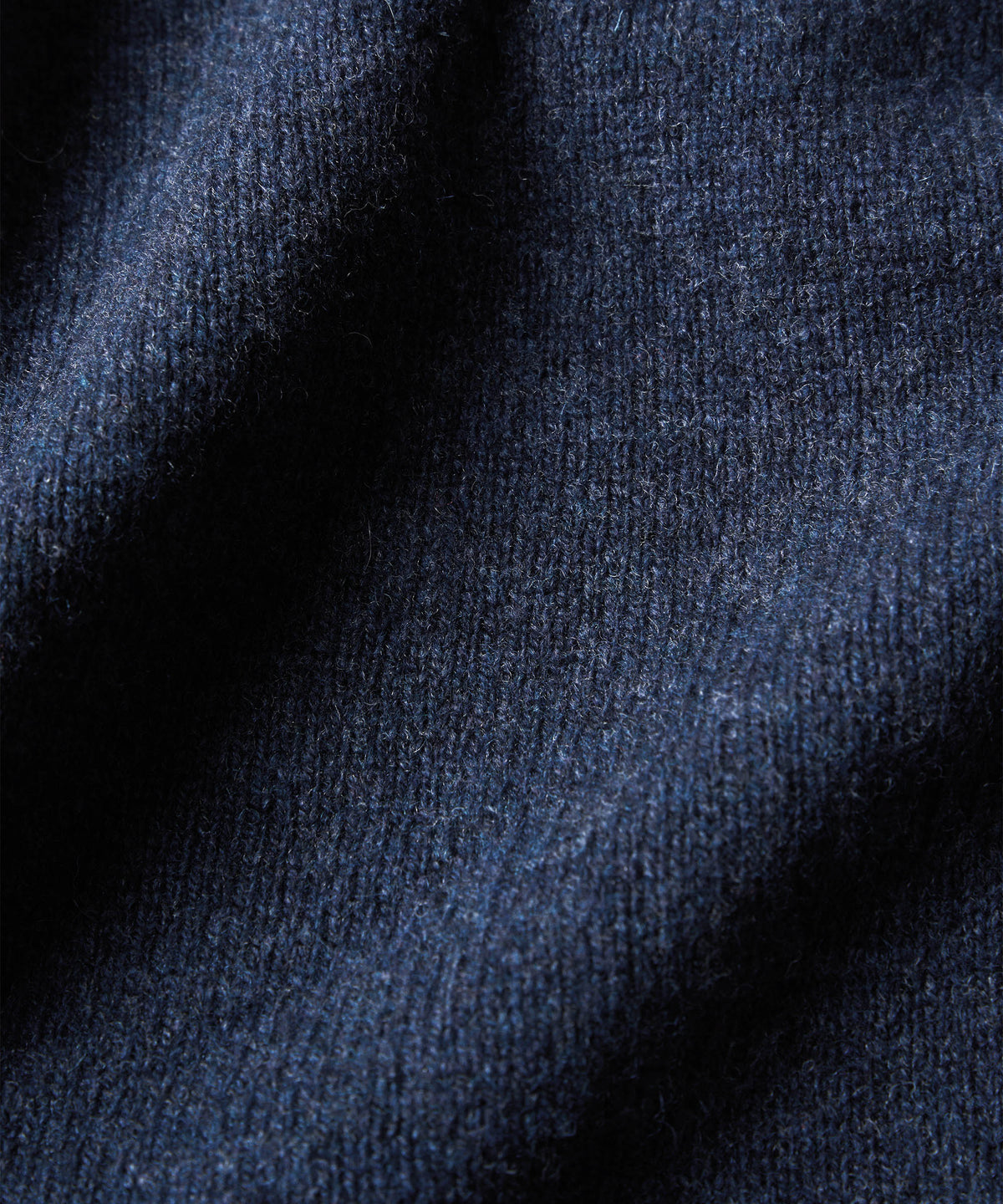 A close-up of dark navy blue knit fabric with soft folds and visible texture.