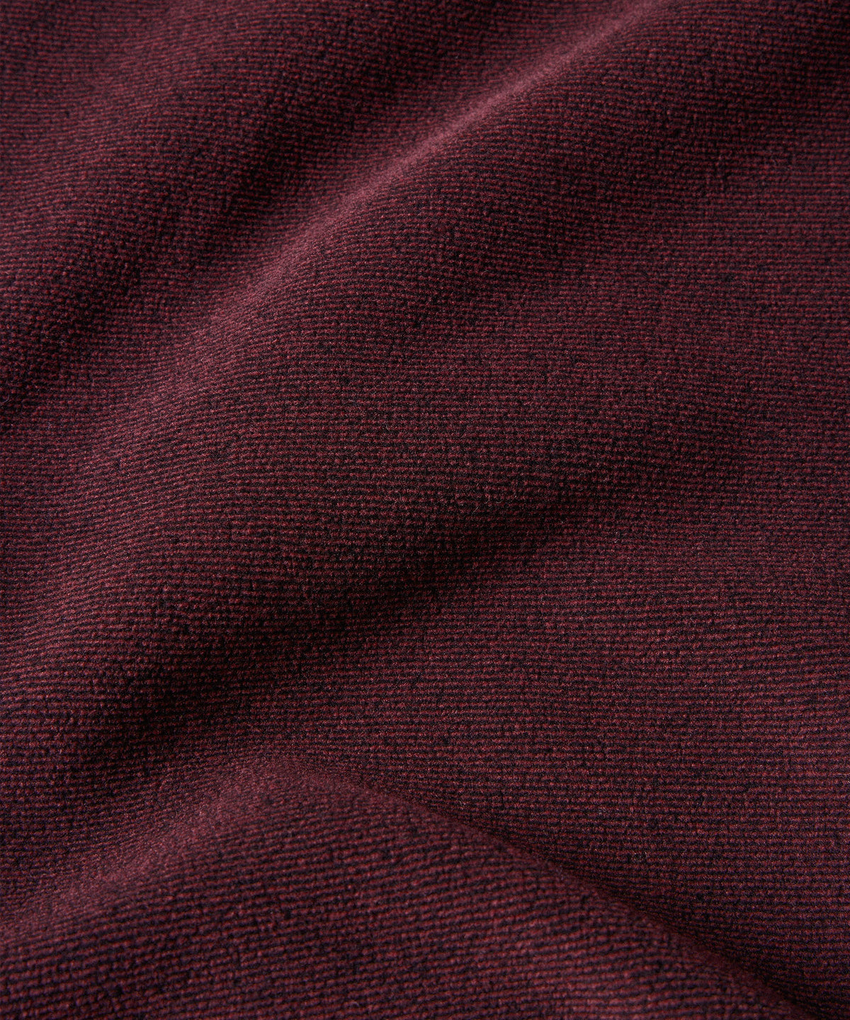 A close-up of textured fleece fabric in a deep burgundy or maroon color.