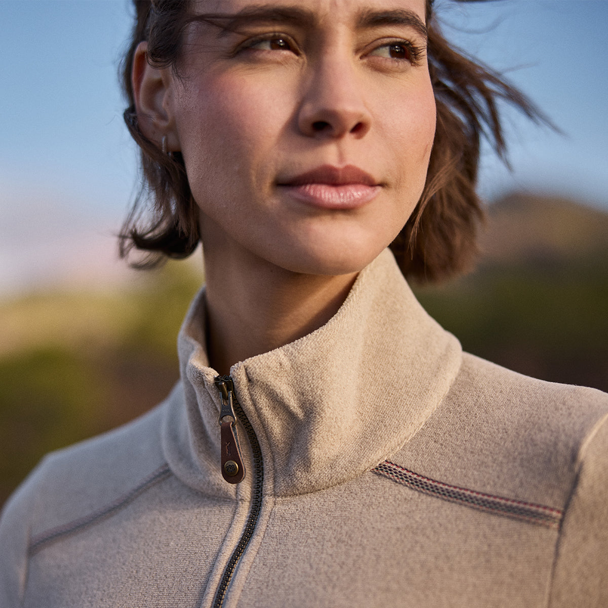 Woman wearing a beige fleece jacket with a blurred natural background