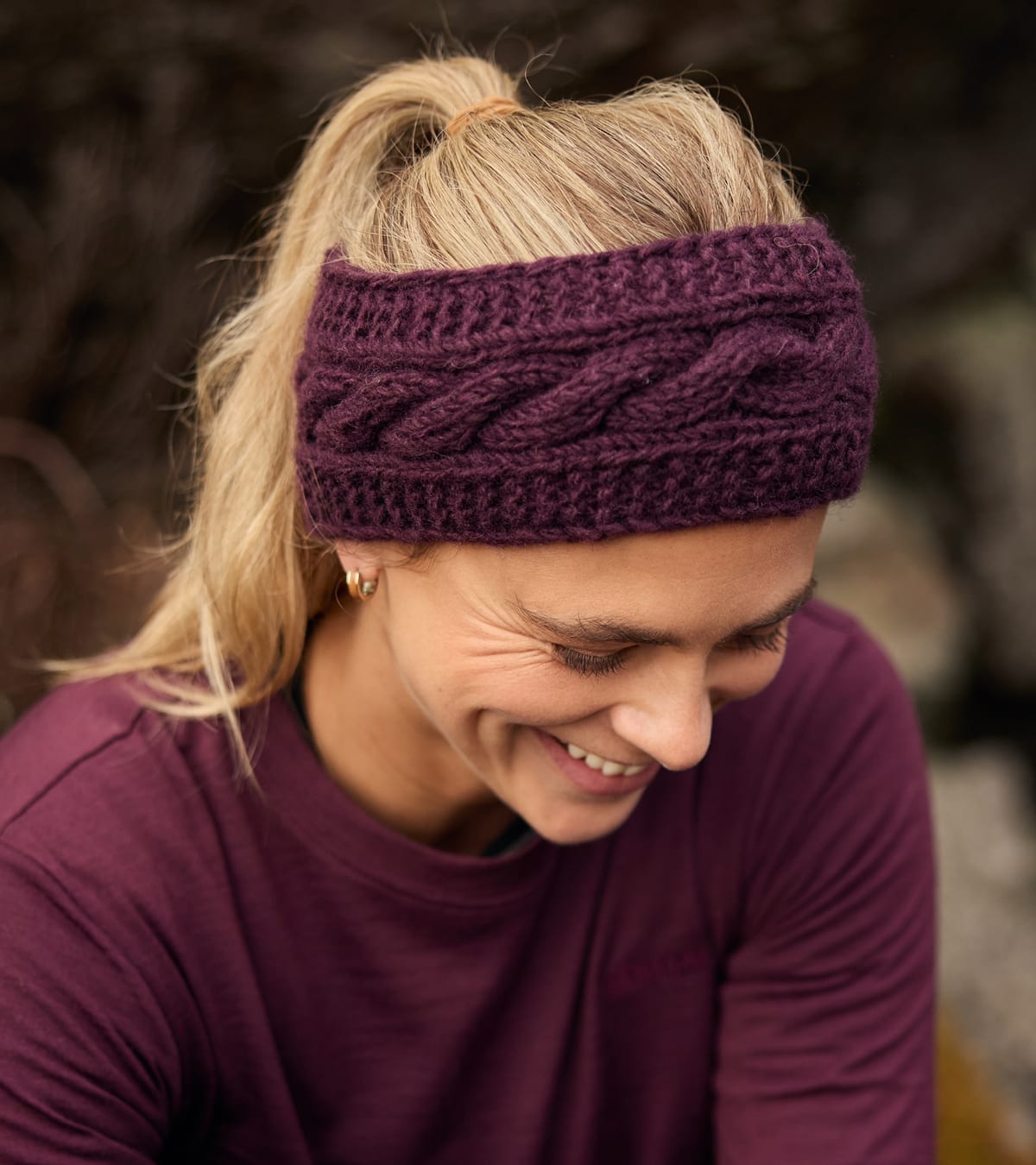 Woman wearing a deep plum cable-knit headband and matching long-sleeve shirt outdoors.
