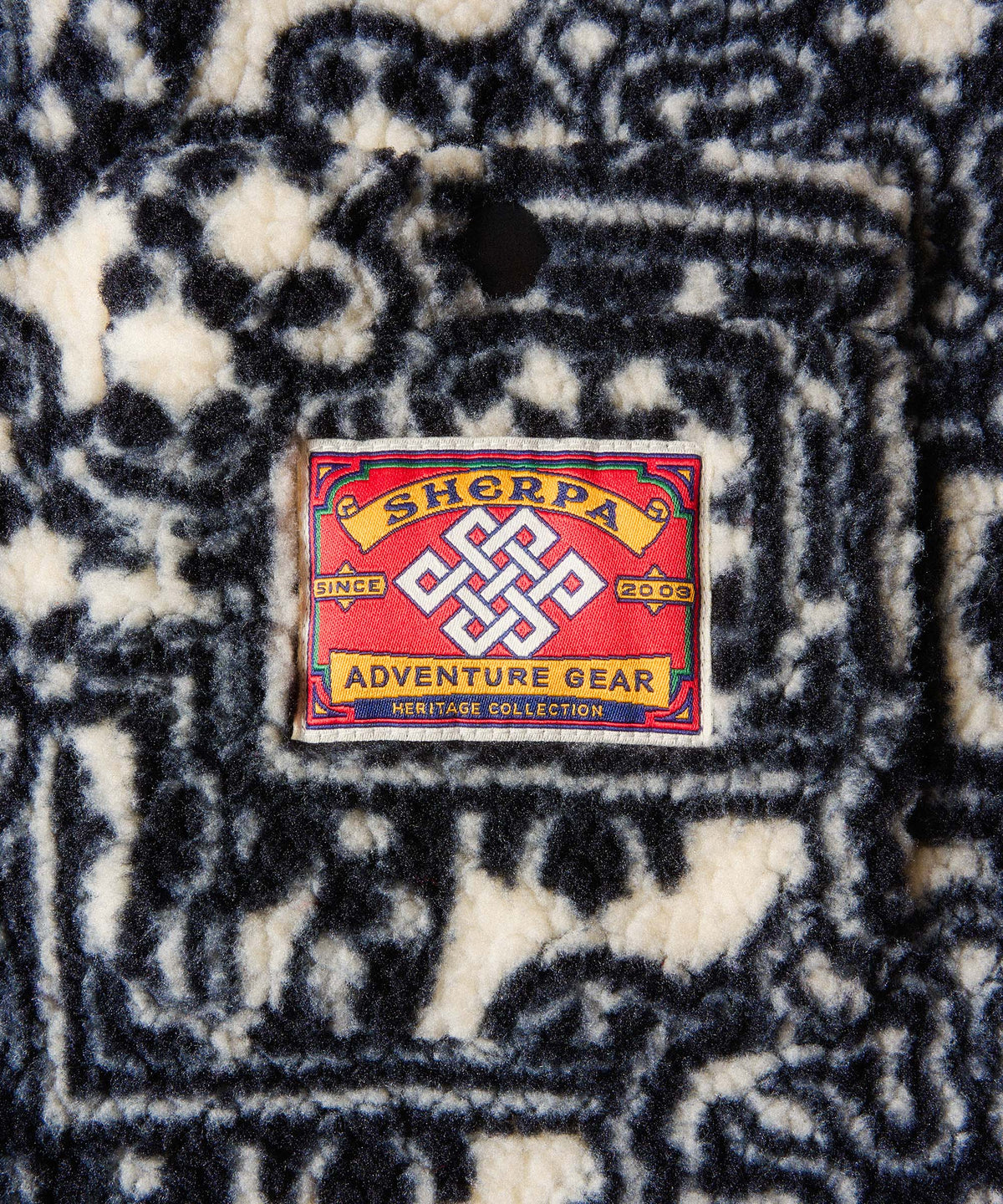Close-up of a sherpa fleece garment with a navy and cream abstract pattern.