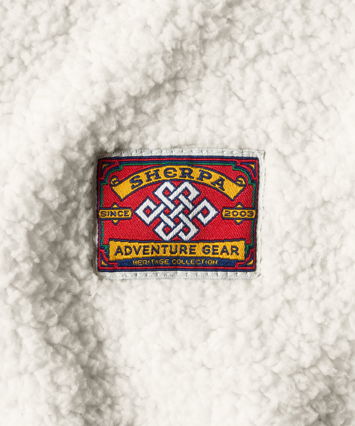 A white fleece fabric with a red patch with yellow lettering.