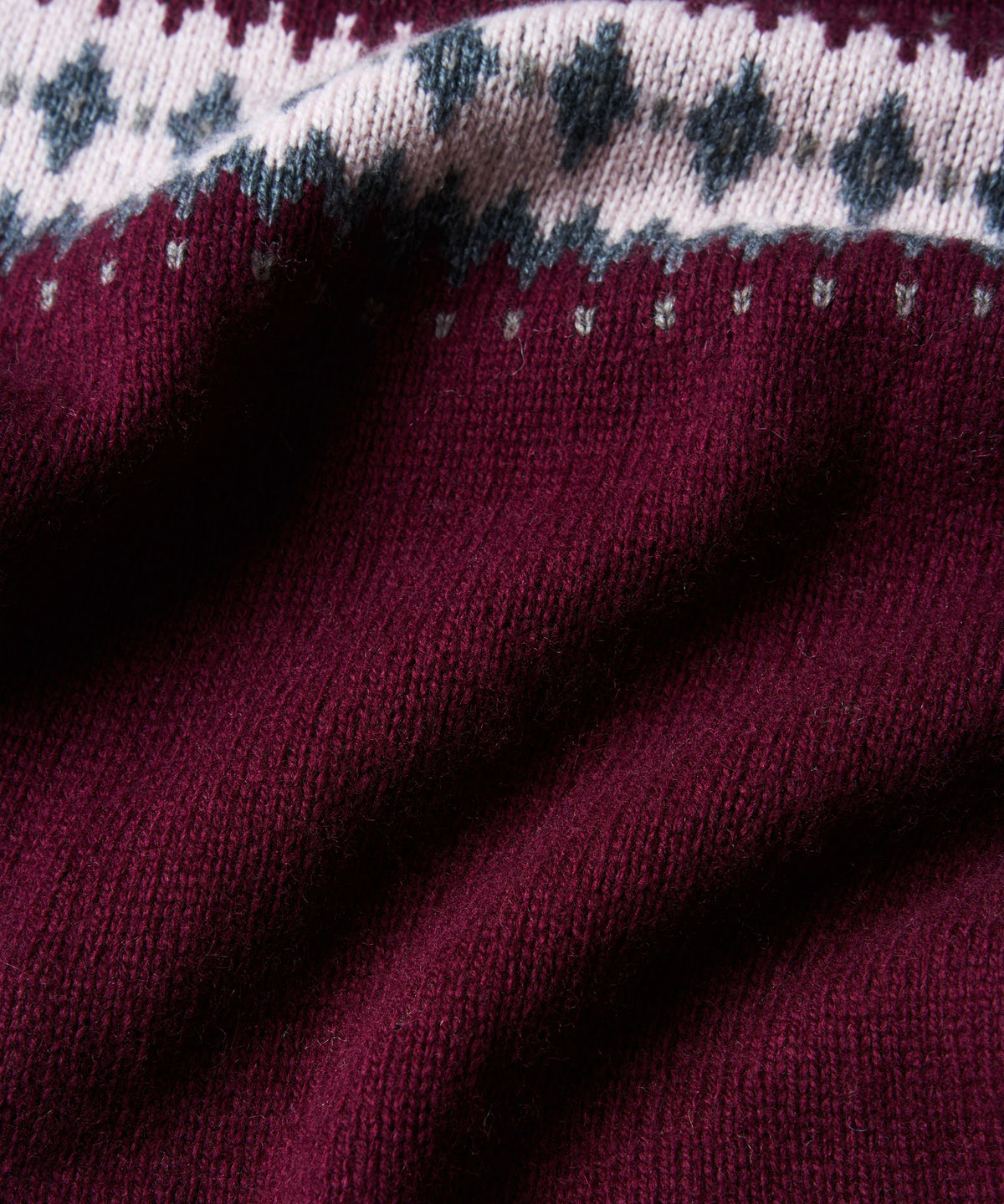 Close-up of a knit fabric with a deep burgundy body and a contrasting white upper band.