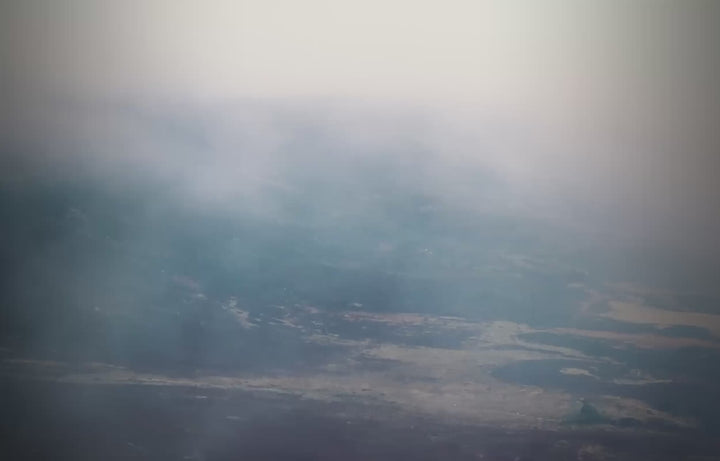 Aerial wide view of a foggy mountain landscape under a light sky.