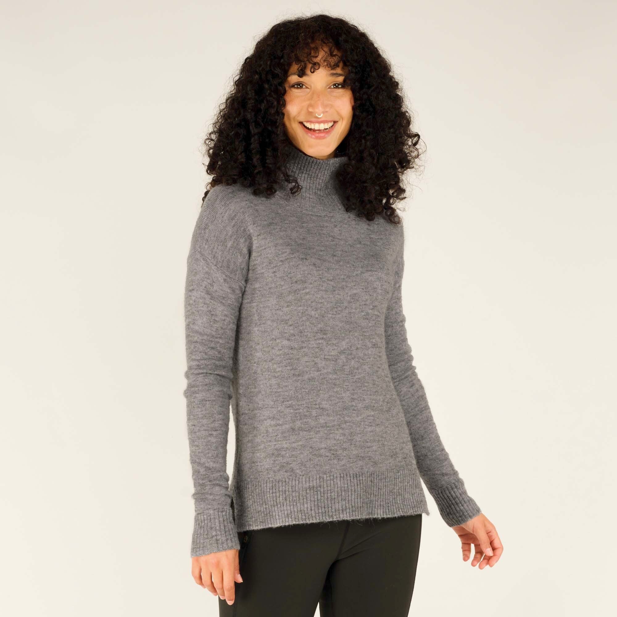 A slightly rotated front view of the model smiling brightly. The relaxed yet tailored fit of the sweater is highlighted, showing its versatility for both casual and semi-formal occasions. The mock-neck design on the Sherpa Adventure Gear Dali Mock Neck in Grey is emphasised, providing both comfort and style.