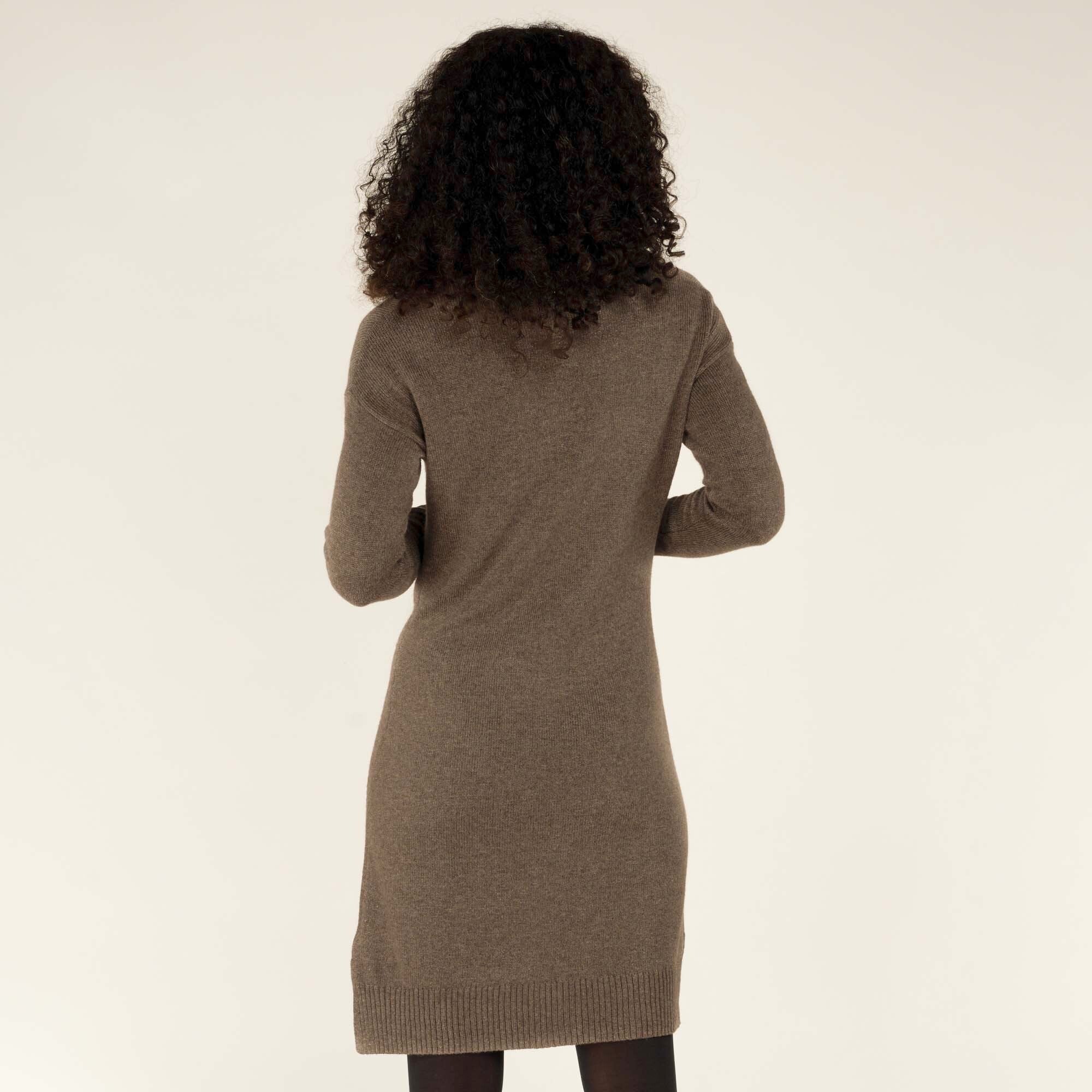 Rear view of the Sherpa Adventure Gear Lhakpa Mock Neck Dress in Grey, emphasising its simplicity and clean lines. The model’s hair cascades over her shoulders, while the ribbed hem and cuffs provide a polished finish to the look.