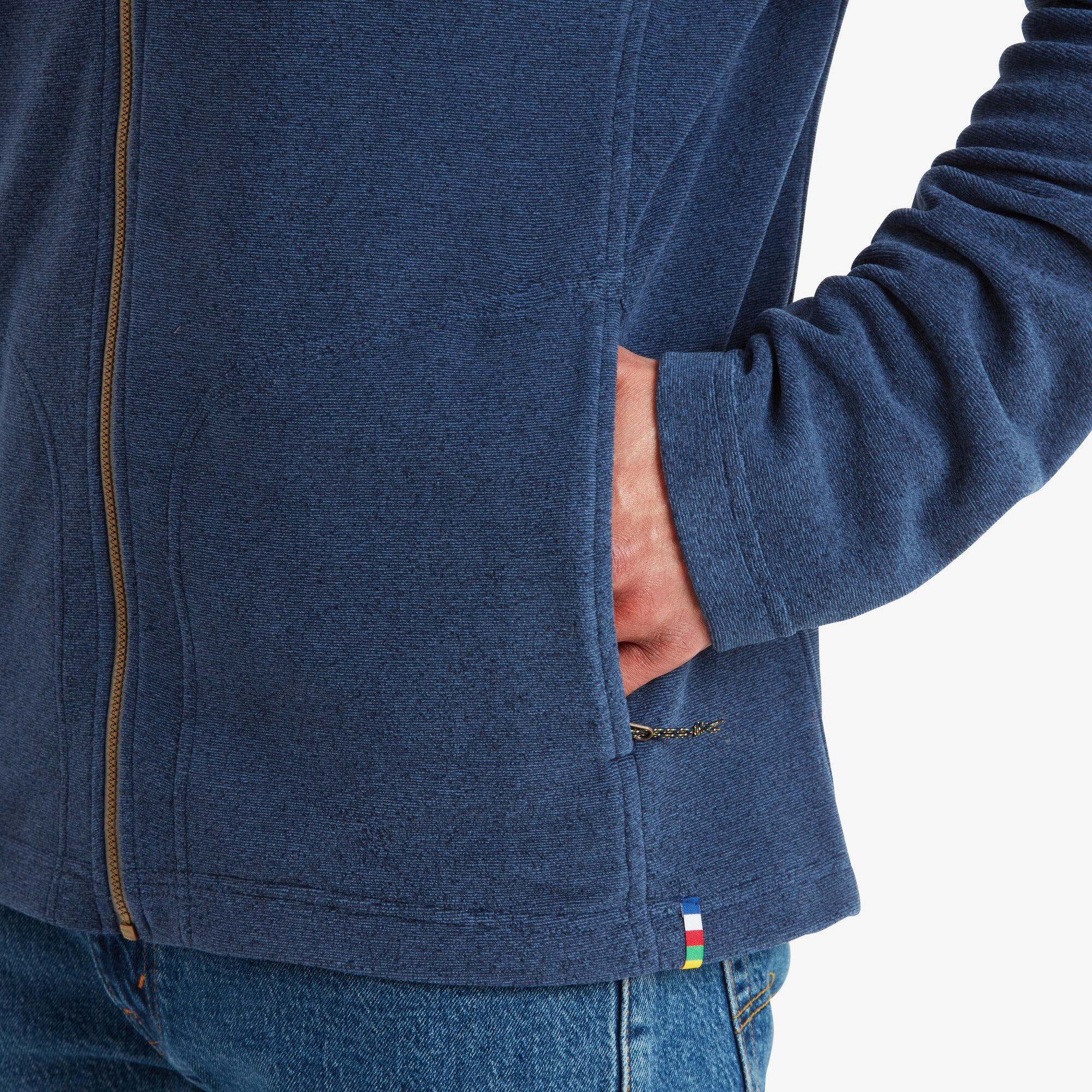 The final image zooms in on the pocket area, highlighting its zippered closure for secure storage. The textured fabric of the Sherpa Adventure Gear Rolpa Eco Jacket in Blue is evident, showcasing its eco-friendly material, and a small Sherpa logo tag is visible near the hem.
