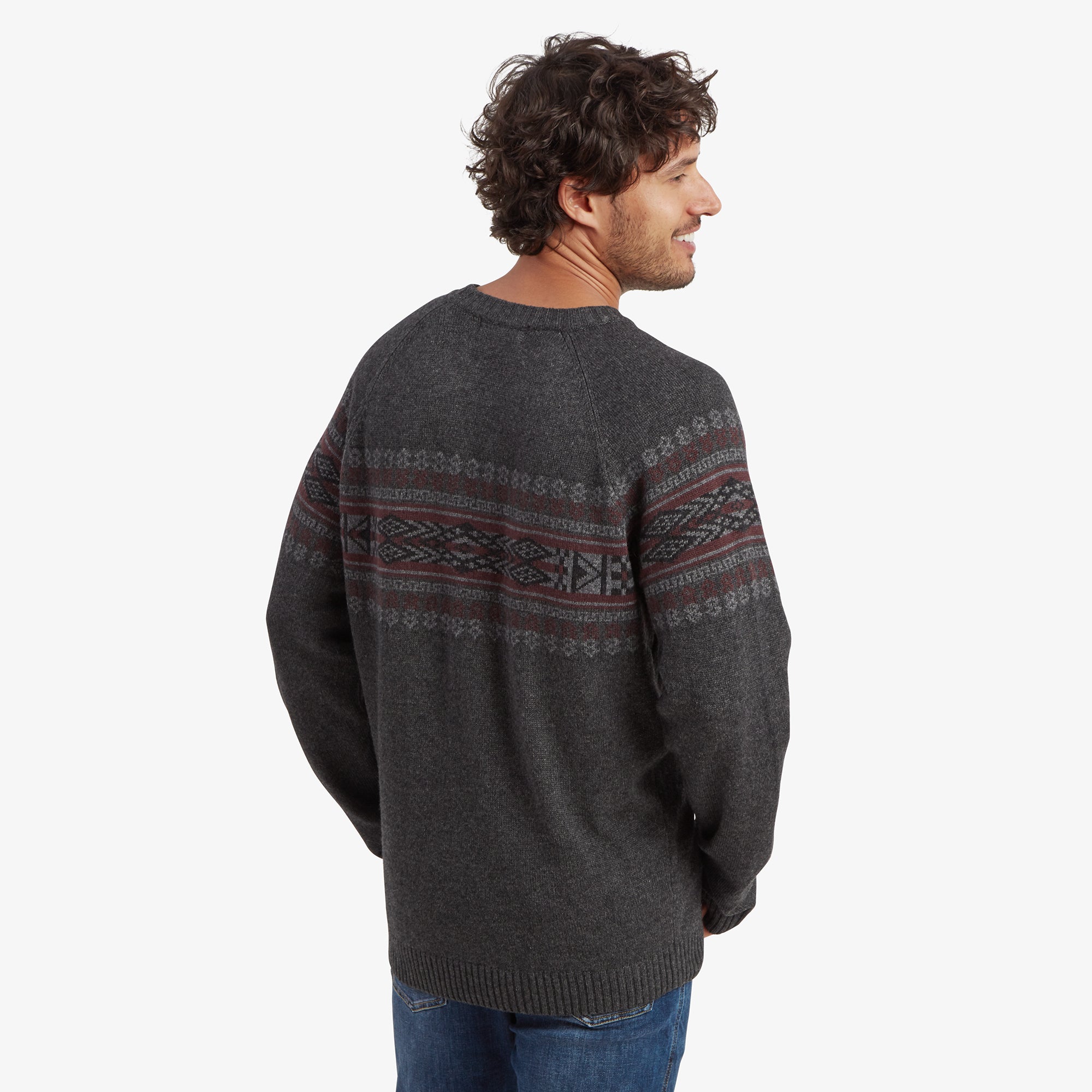 A back view of the Sherpa Adventure Gear Sajit Eco Crew in Grey, displaying the continuation of the patterned design across the shoulders and back. The man’s relaxed pose showcases the sweater’s comfortable fit from behind.