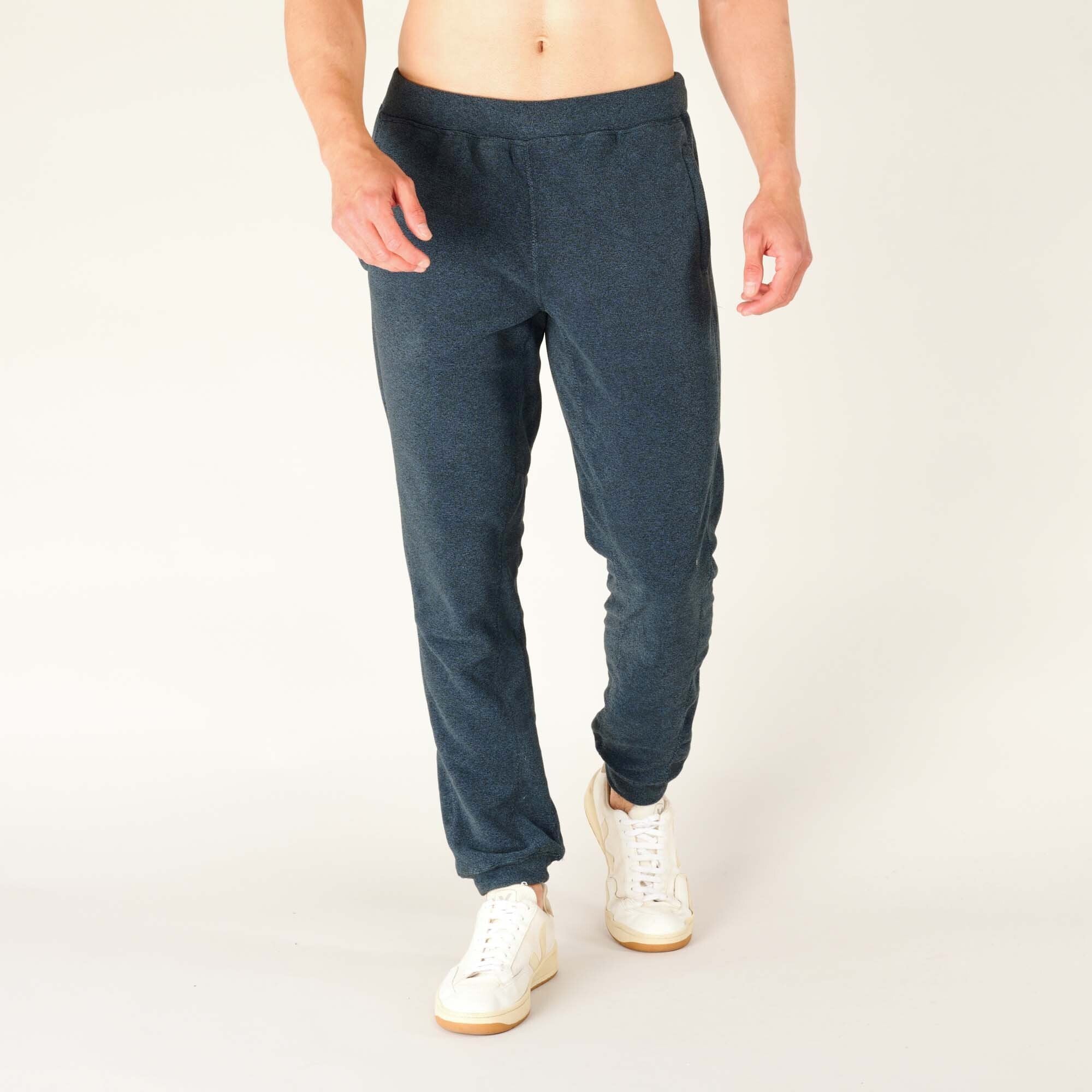 Walking view from the front, capturing the natural movement of the Sherpa Adventure Gear Rolpa Jogger in Blue. The soft fleece fabric flexes easily, and the ankle cuffs keep the fit tidy.
