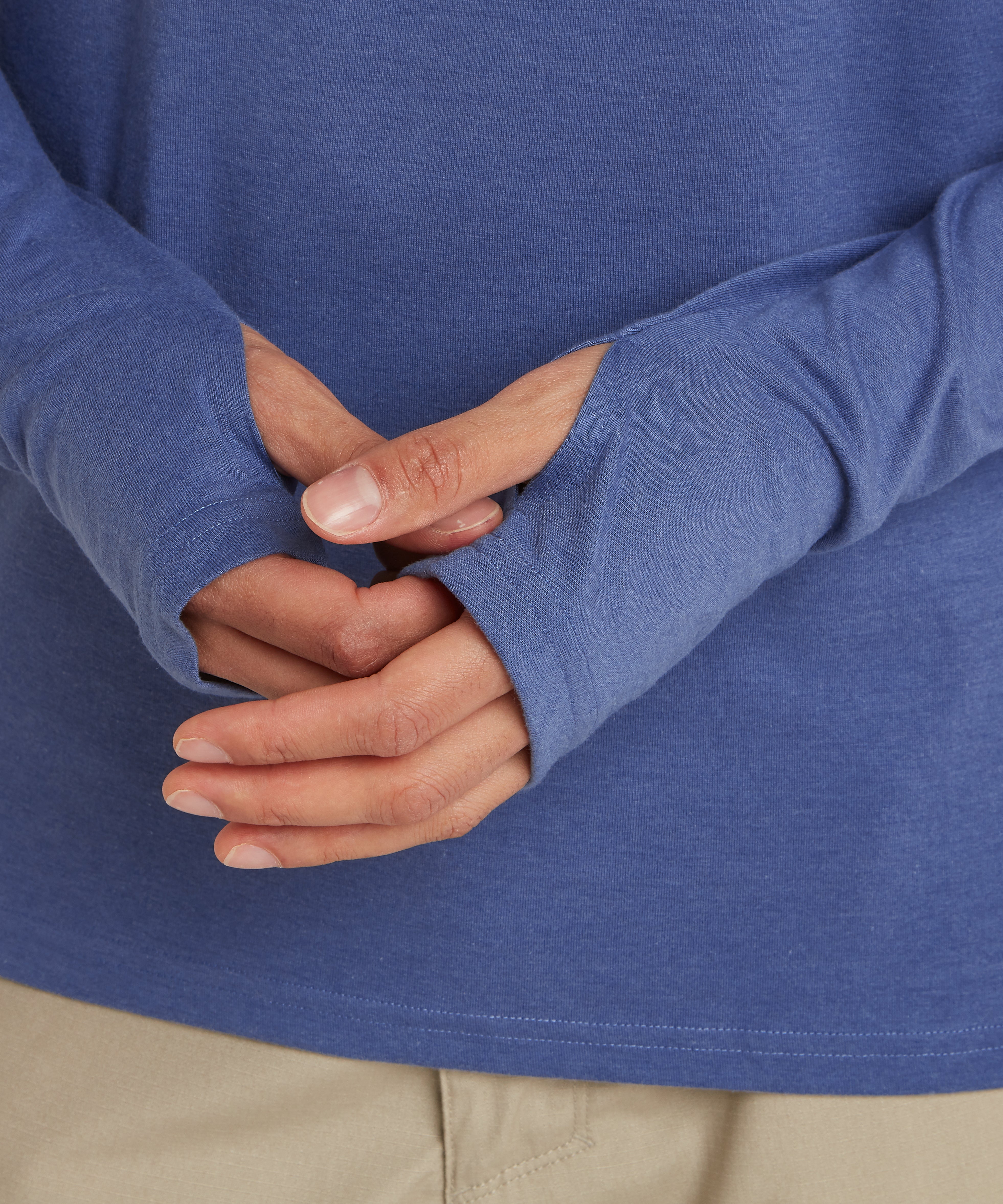 A close up of a man wearing a light blue hoodie. The cuffs and sleeves of the hoodie are visible. The cuffs feature thumb loops on both hands. The man is adjusting his right cuff.