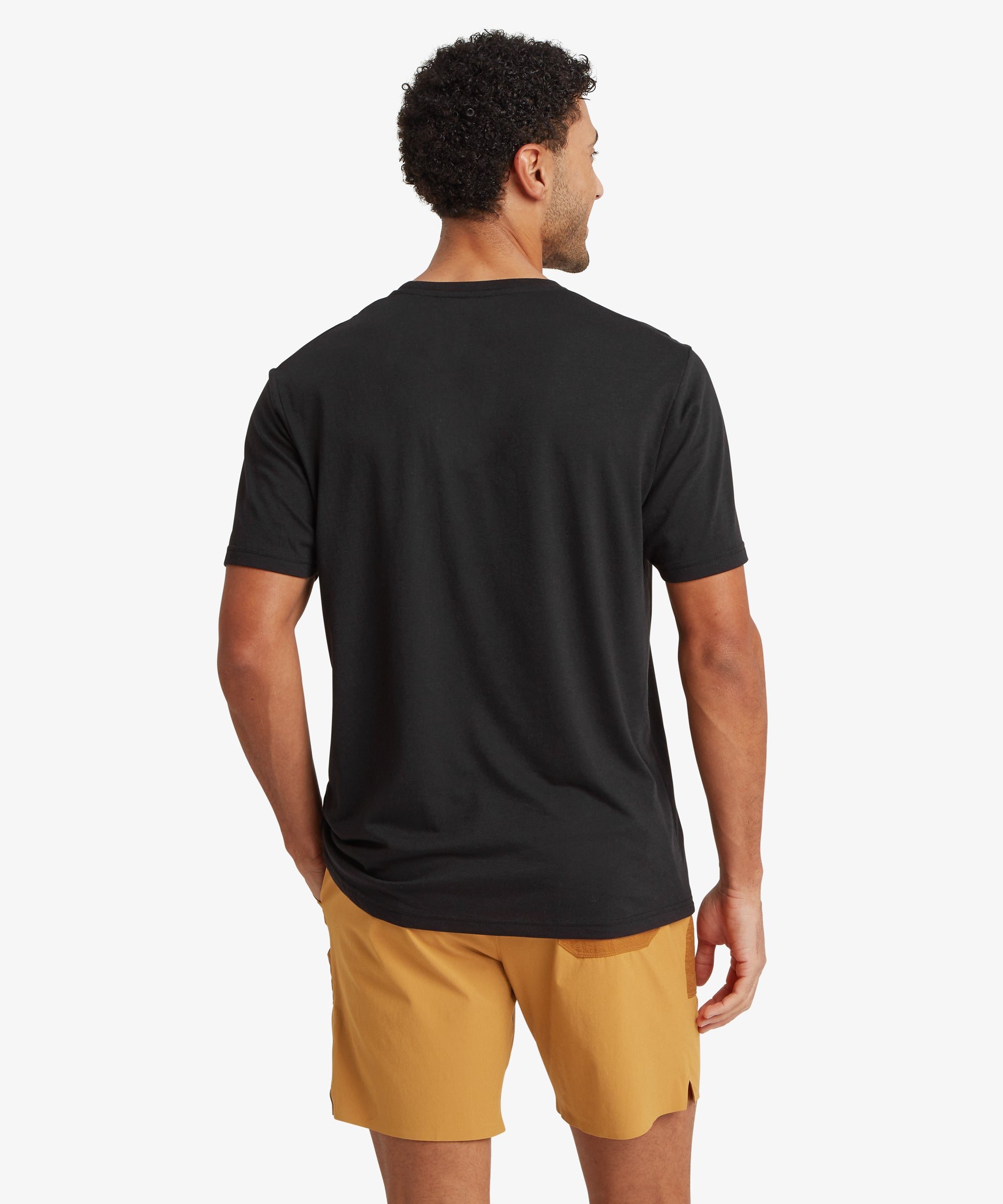 Rear view of a person wearing a black T‑shirt and mustard shorts.