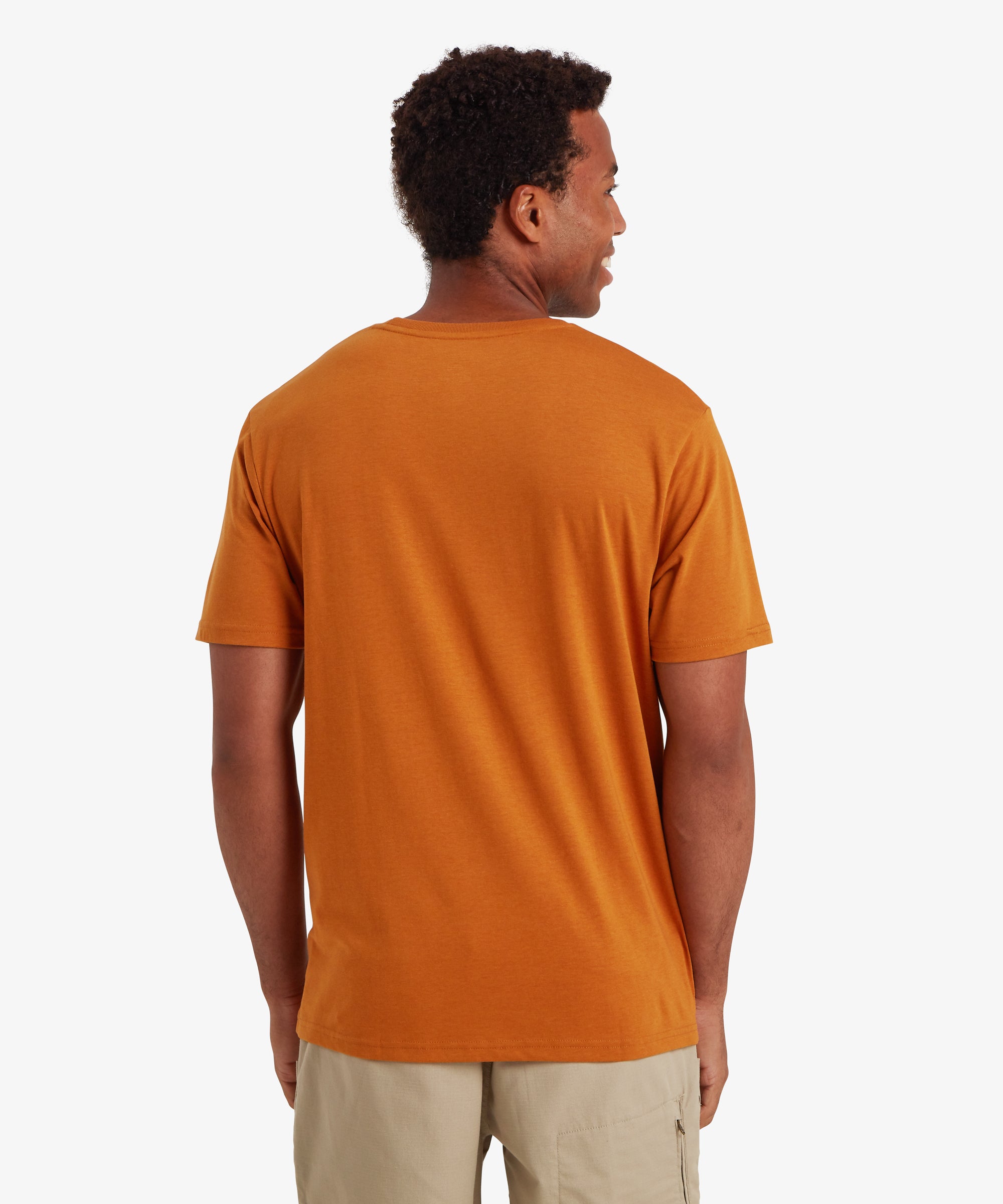 A back view of a man wearing a rust orange classic fit t-shirt. The short sleeve t-shirt is styled a pair of beige shorts. The man's head is turned to the right and he has both hands down by his side.