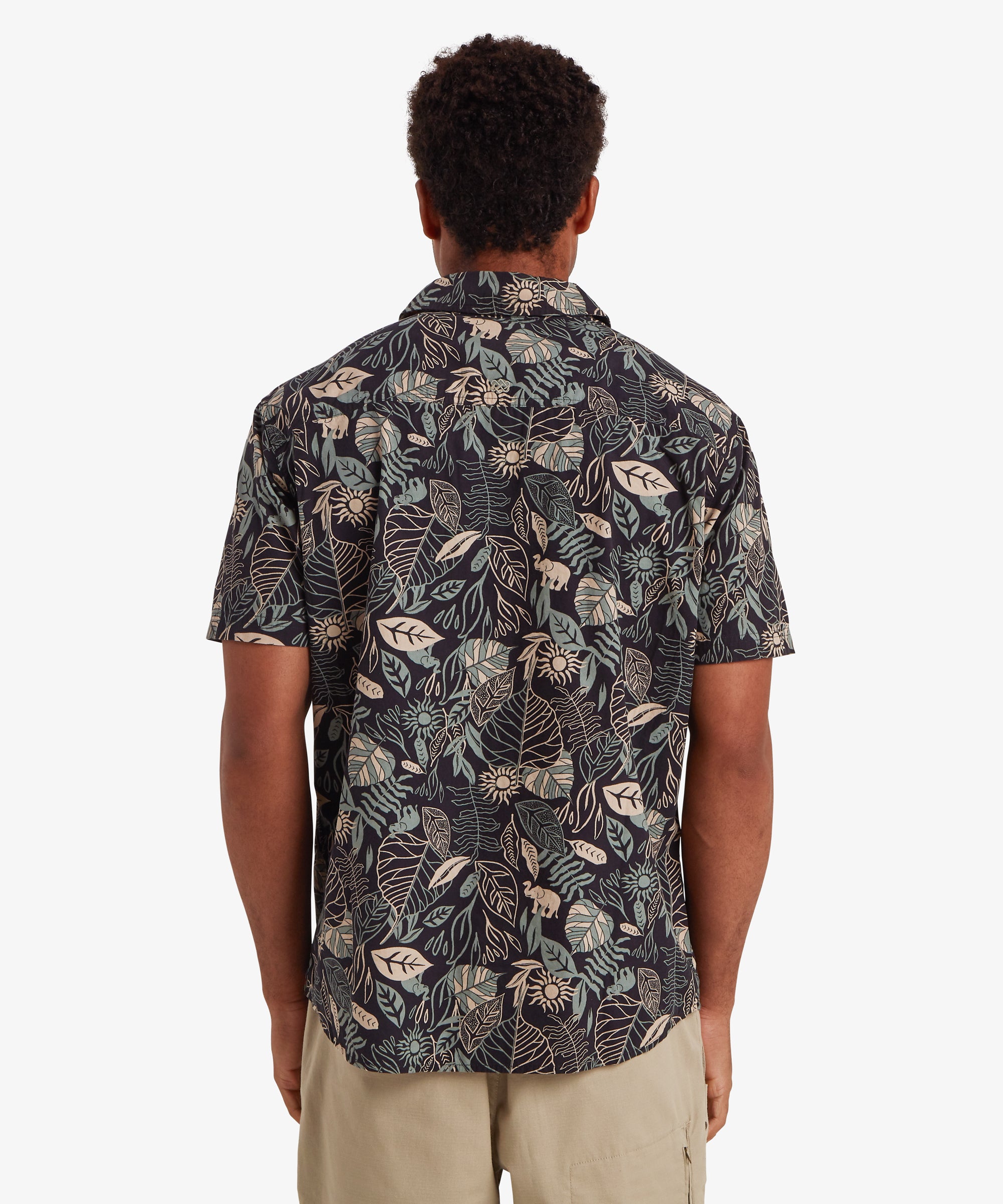 RŸckansicht eines Mannes, der ein schwarzes Kurzarmhemd mit Knšpfen trŠgt. Das Hemd ist mit einem botanischen Blattmuster in hellen Creme- und Blautšnen bedruckt. Dazu trŠgt er beige Shorts mit einer Seitentasche mit Rei§verschluss. Der Mann hat kurzes schwarzes Haar und steht mit den HŠnden an den Seiten.