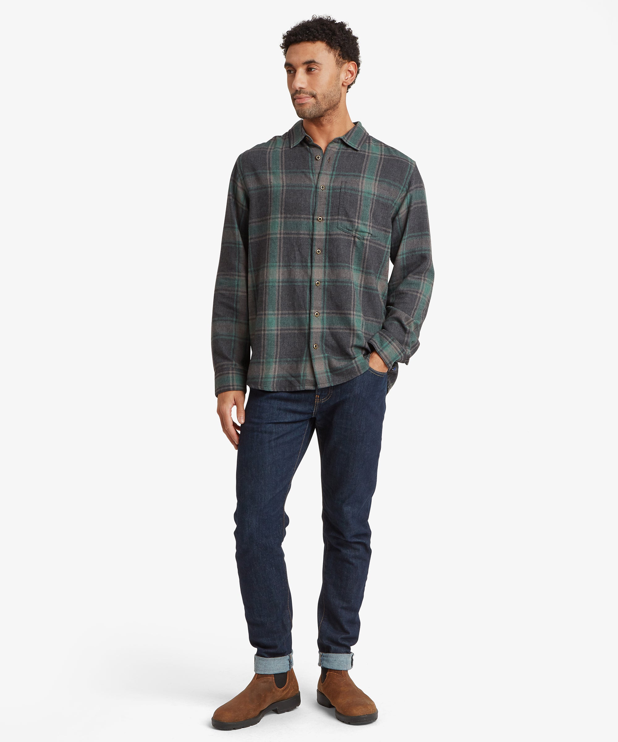 A man modeling a long-sleeve button-up plaid shirt in dark green, gray.