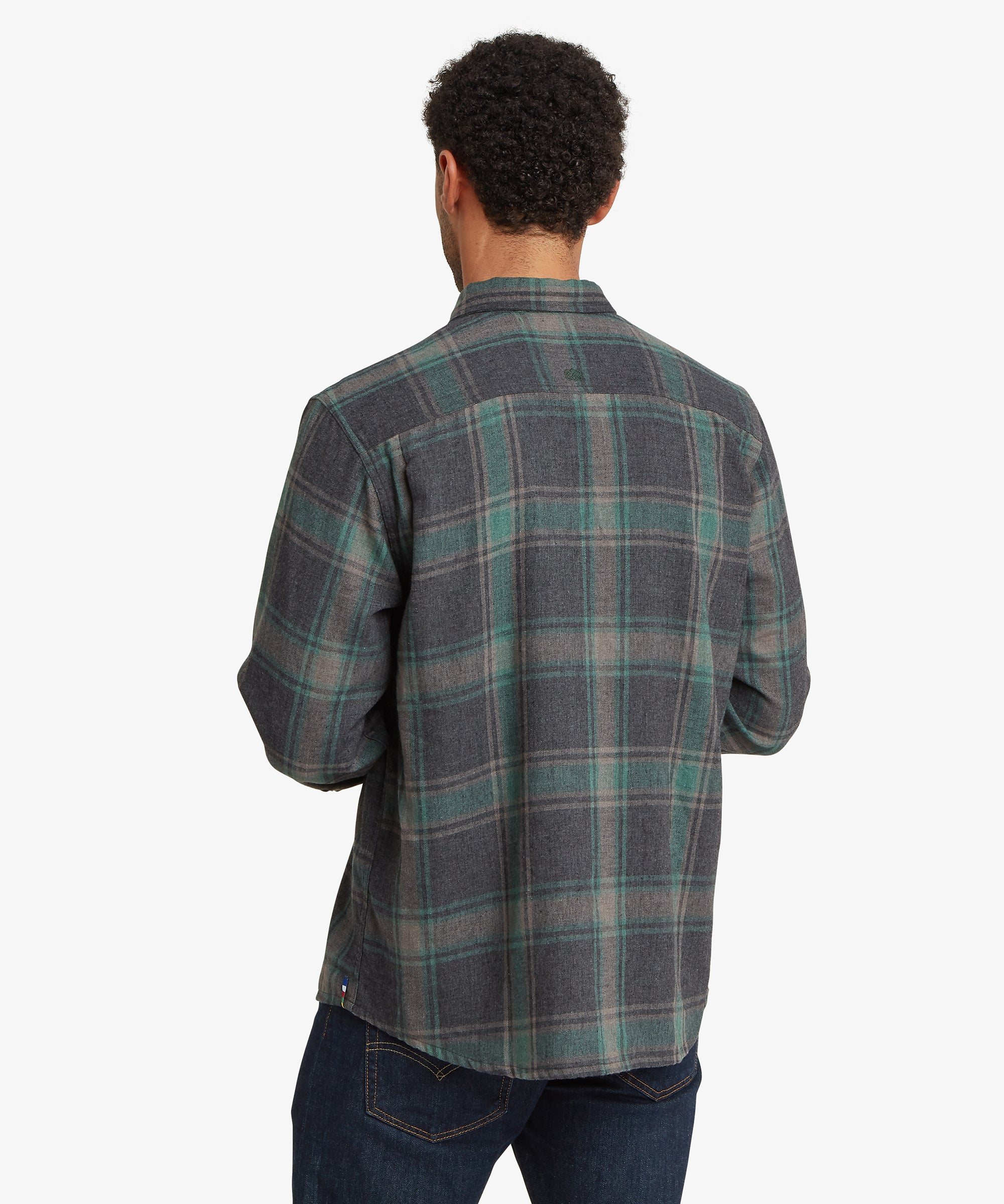A man viewed from behind wearing a long-sleeve plaid button-up shirt in dark gray.