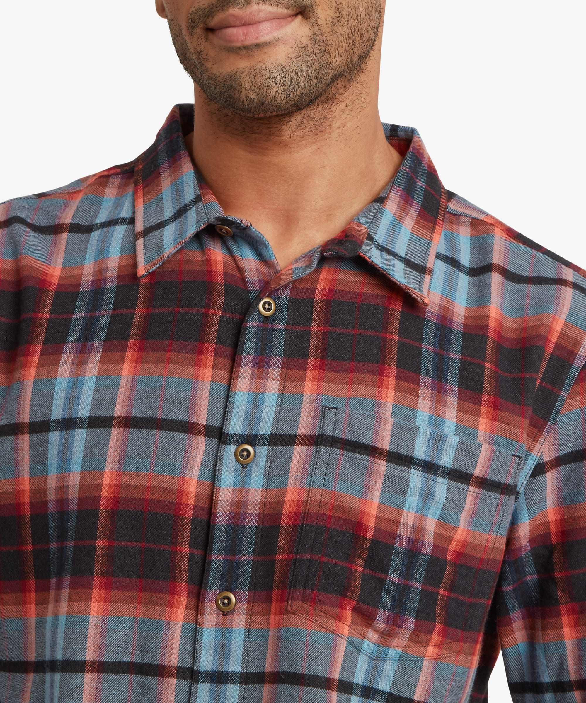 Close-up of the collar and upper chest area of a red plaid shirt showing the classic collar, button-front placket and multicoloured woven check pattern.