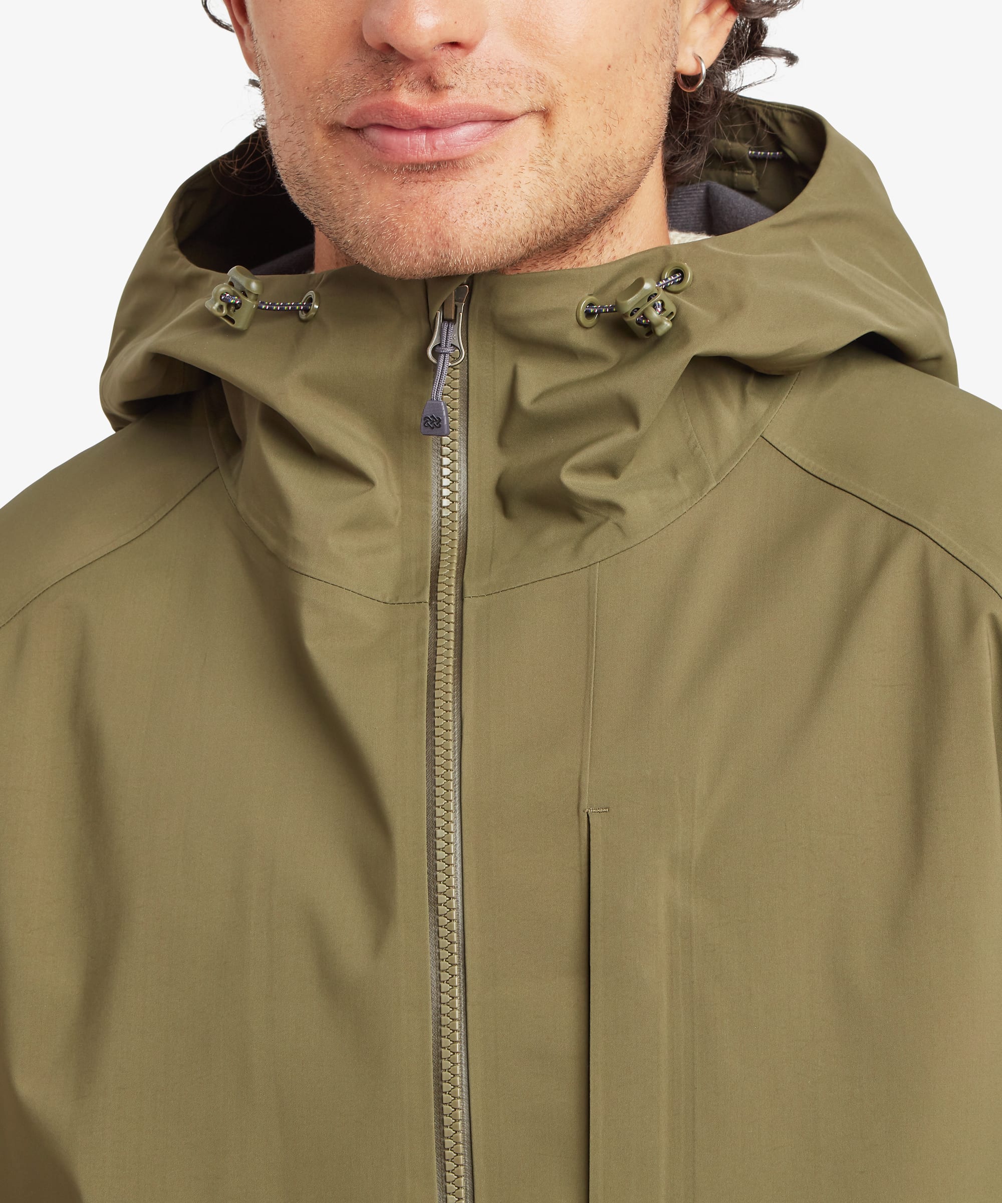Close-up of the upper front of an olive green shell jacket showing the waterproof zip closure, high protective collar, adjustable hood drawcords and technical outdoor design details.